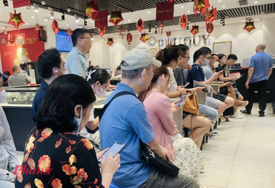 Cách cửa hàng trên không xa,  người dân ngồi chờ theo hàng lối, trật tự để thực hiện giao dịch theo quy định tại cửa hàng vàng bạc Phú Quý (số 329 Cầu Giấy).