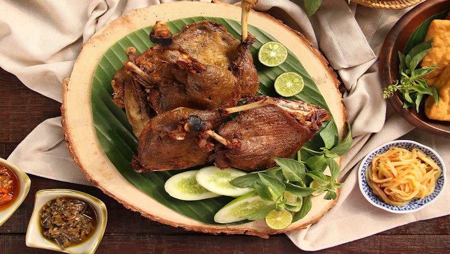 Bebek Goreng là món vịt chiên giòn nổi tiếng khắp Indonesia, được yêu thích bởi lớp da vàng ruộm, giòn tan và phần thịt bên trong mềm thơm, đậm vị. Thịt vịt sau khi được luộc sơ cùng sả, gừng, nghệ và lá chanh để khử mùi, sẽ được ướp tiếp với tỏi, hành tím và gia vị truyền thống trước khi chiên vàng trong chảo dầu sôi. Nhờ cách chế biến này, thịt vịt vẫn giữ được độ ngọt tự nhiên mà không bị khô, trong khi lớp da ngoài lại giòn rụm, dậy hương thơm hấp dẫn.