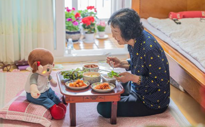 Oh Buk-im, sống một mình ở Mokpo, tỉnh Nam Jeolla, ăn bữa ăn với một robot chăm sóc ngồi đối diện cô