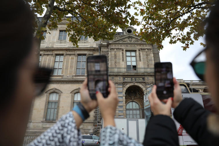 Khách du lịch chụp ảnh cửa sổ bị vỡ nơi bọn trộm đột nhập vào bảo tàng Louvre - Ảnh: Mohamad Salaheldin Abdelg Alsayed/Anadolu 