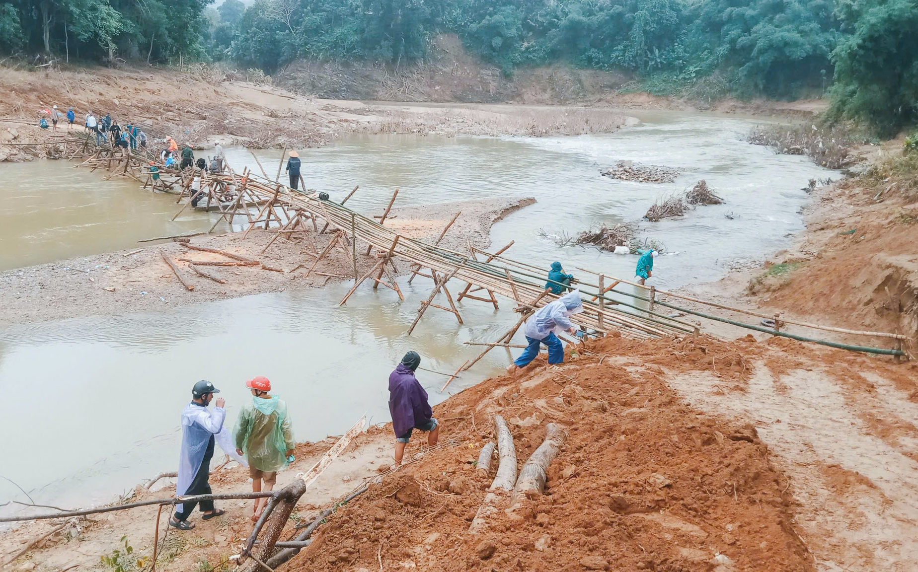 Cây cầu tạm bằng tre nứa dài khoảng 60m được dựng ngay bên cầu cứng bị lũ cuốn trôi - Ảnh: Khánh Trung