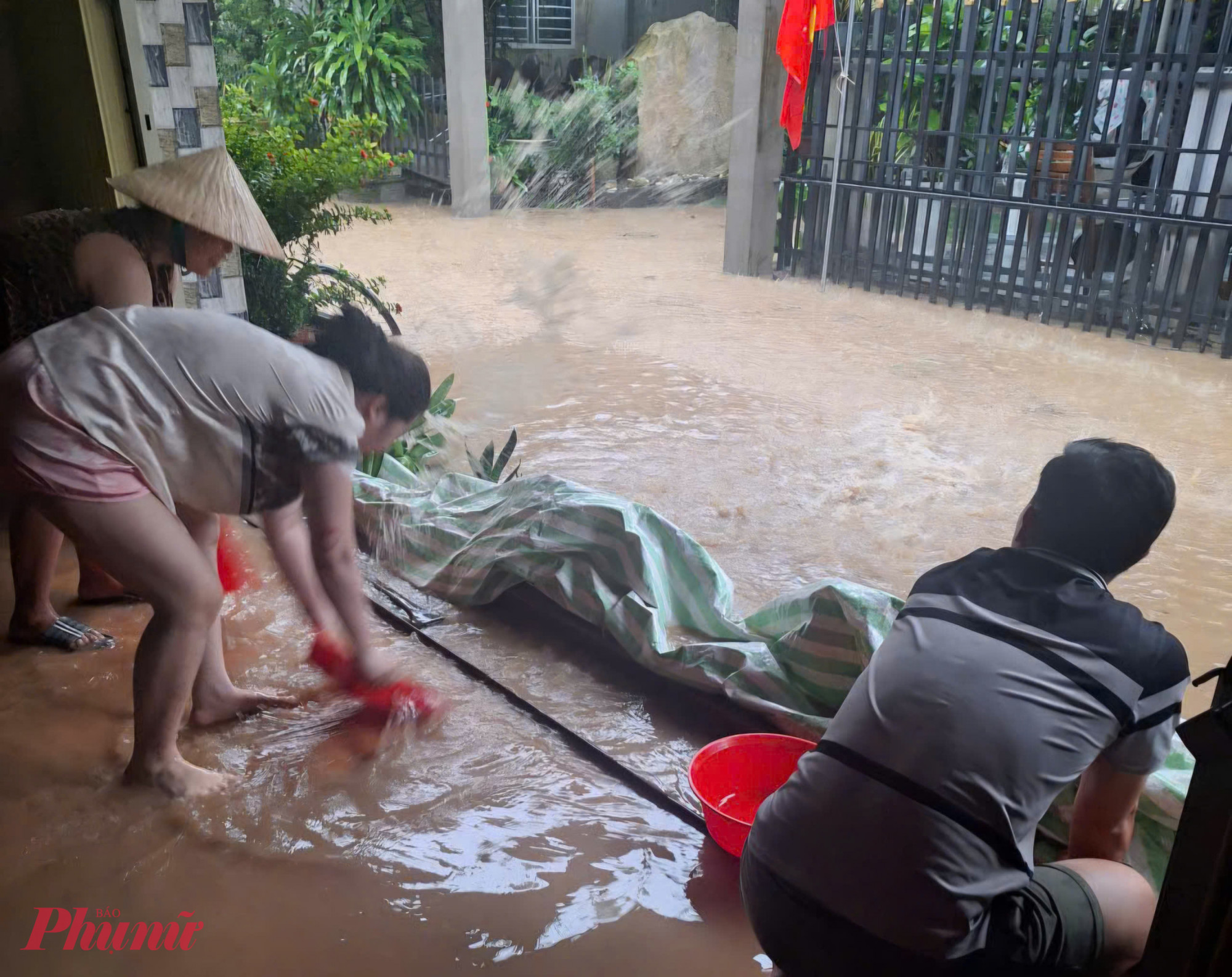 Người dân chật vật ngăn nước vào nhà - Ảnh Quốc Gia