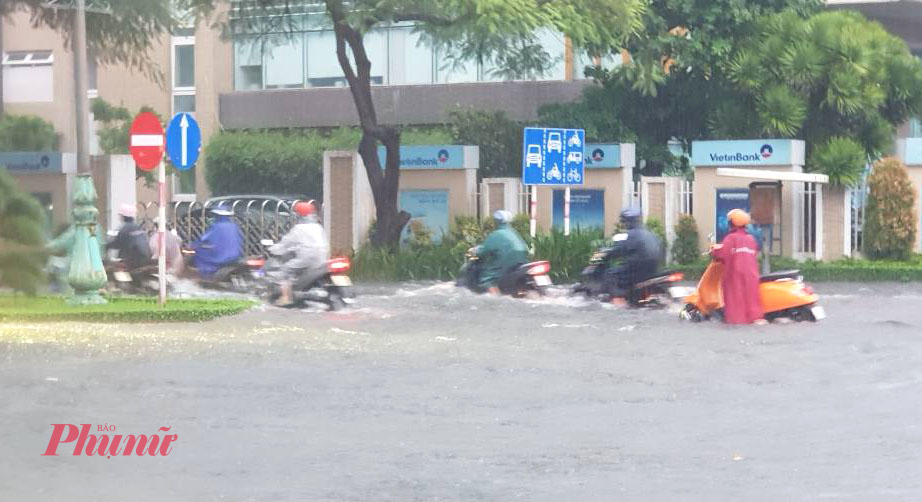 Rất nhiều người phải dắt xe lội bì bõm vì xe bị ngập nước, chết máy đường Hùng Vương. Ảnh: NK
