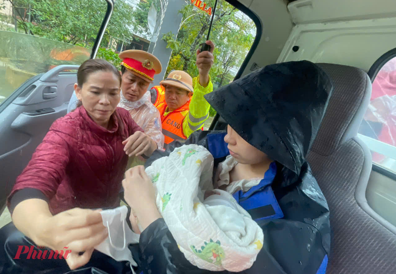 Nước tràn vào nhà, ngập sâu gần 80cm, chị Hồ Hoàng Thi (trú tổ dân phố An Đông, phường An Cựu) cùng con nhỏ 7 ngày tuổi được lực lượng CSGT hỗ trợ di dời đến nơi an toàn.