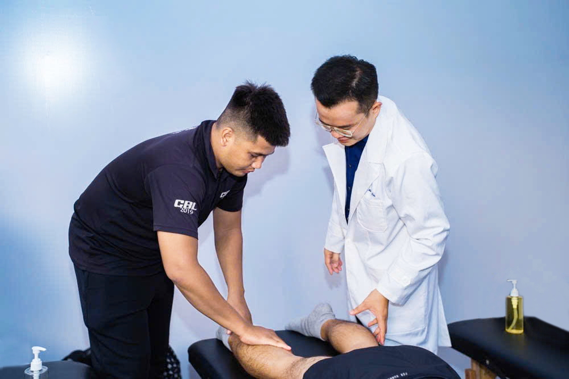 Bác sĩ thể thao Phạm Minh Tiện (bìa phải) hướng dẫn giãn cơ cho vận động viên - Ảnh do bác sĩ cung cấp