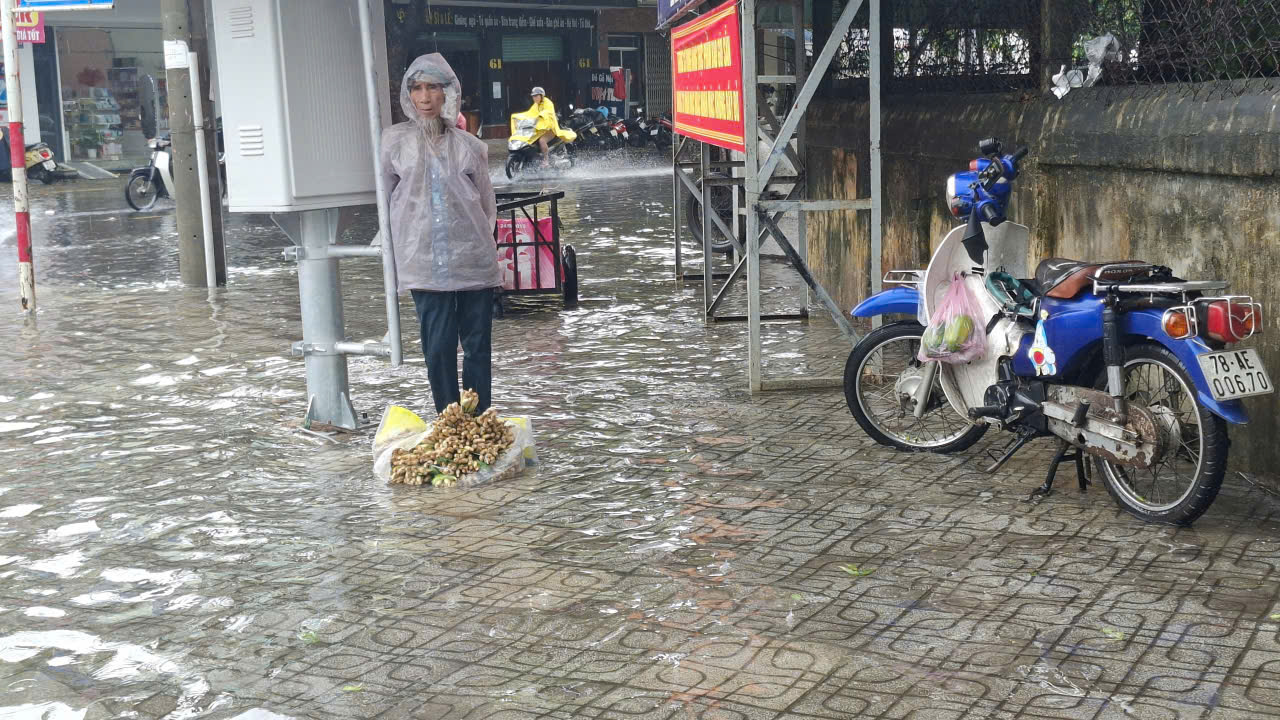 Mưa to đường phố Tuy Hòa thành biển nước, người dân họp 'chợ nổi' Cụ già bán sả bị ngập chỗ ngồi góc đường Lê Thành Phương- Nguyễn Huệ, phường Tuy Hòa-- Ảnh: Mạnh Hoài Nam