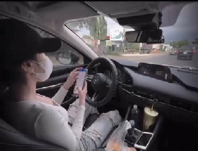Cô gái thả 2 tay, lướt điện thoại khi điều khiển ô tô - Ảnh: cắt từ clip trên mạng xã hội