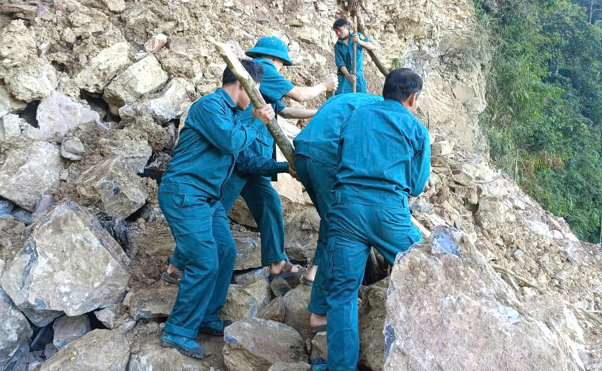 Các lực lượng chức năng phải leo lên các vách núi cạy phá những tảng đá treo lơ lửng - Ảnh: Khánh Trung