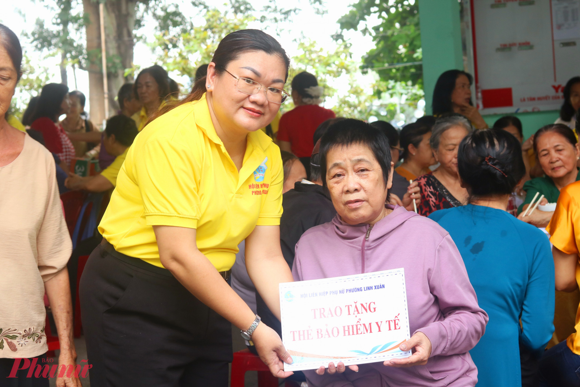 Bà Nguyễn Thị Phương Thùy - Phó chủ tịch Ủy ban MTTQ, Chủ tịch Hội LHPN phường Linh Xuân – trao bảng tượng trưng tặng thẻ bảo hiểm y tế đến các dì hội viên, phụ nữ thuộc diện hộ cận nghèo - Ảnh: Mẫn Nhi