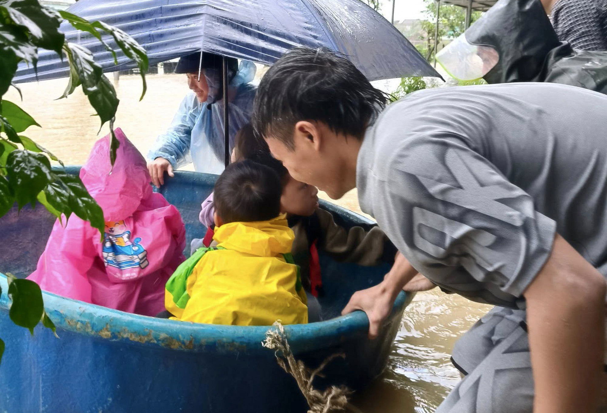 Phụ huynh dùng thuyền thúng đón học sinh về nhà do đường bị ngập sâu - Ảnh: Thu Hương