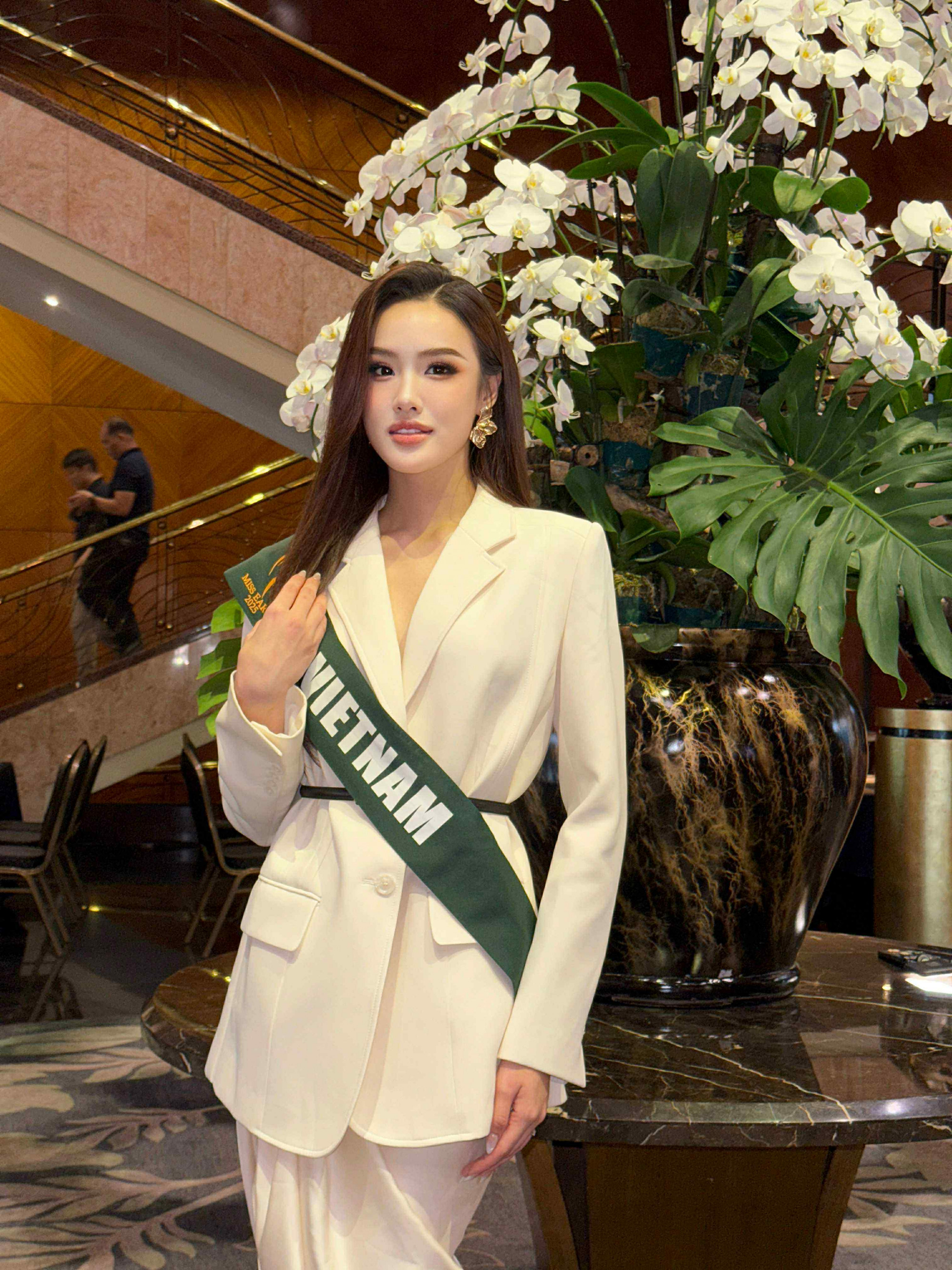 Trịnh Mỹ Anh toát lên phong thái thanh lịch và hiện đại trong bộ suit trắng tinh khôi. Thiết kế vest dáng dài, chiết eo nhẹ kết hợp cùng quần ống suông tạo nên vẻ ngoài vừa mạnh mẽ, vừa nữ tính. Chiếc thắt lưng nhỏ đen giúp cân bằng tông màu và làm nổi bật vòng eo thanh mảnh, trong khi chất liệu vải cao cấp mang lại cảm giác sang trọng. Người đẹp khéo léo chọn khuyên tai bản lớn ánh vàng làm điểm nhấn, tôn lên gương mặt sắc sảo và thần thái tự tin.