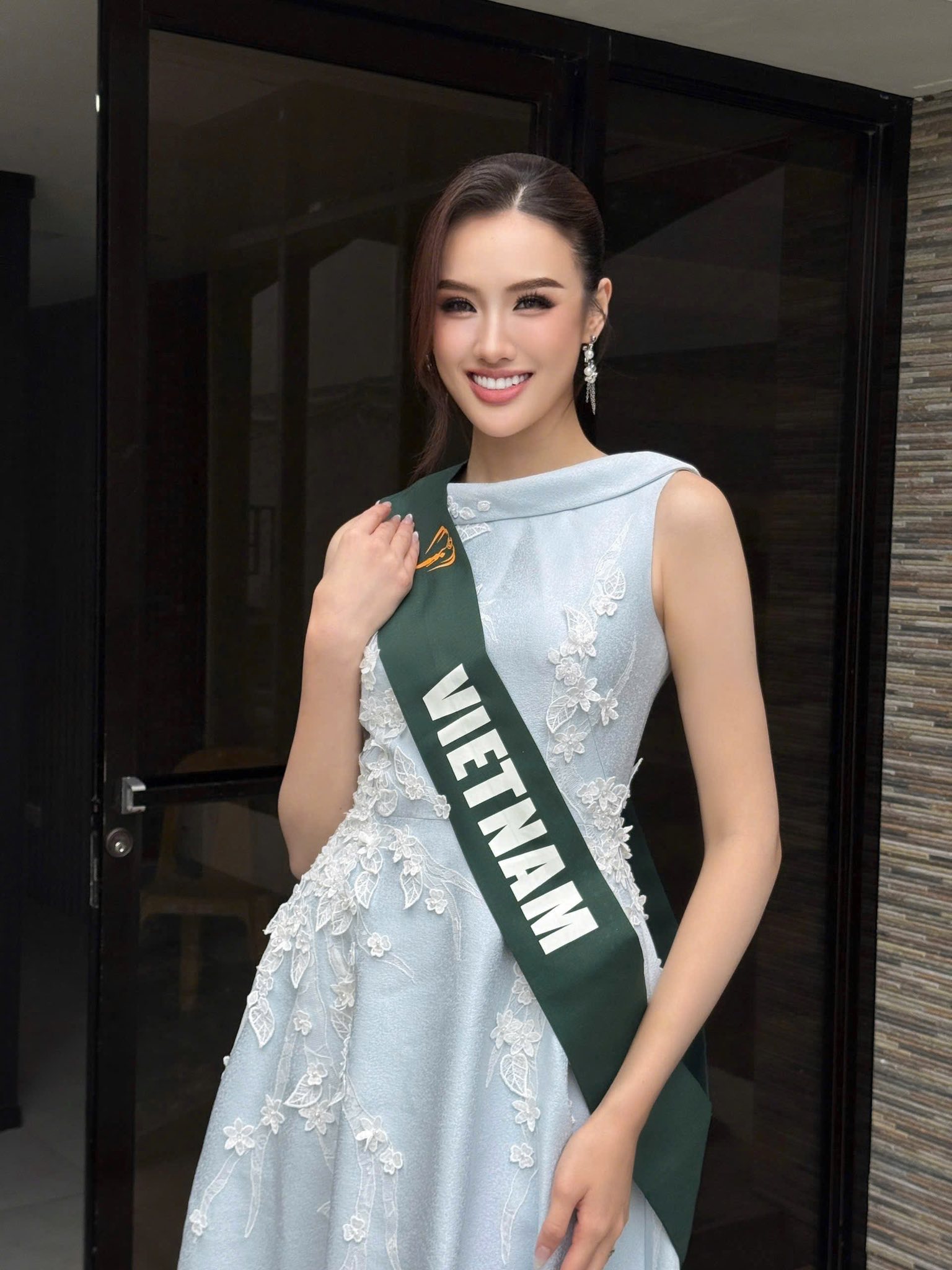 ghi điểm với vẻ đẹp ngọt ngào và thanh thoát trong chiếc váy dạ hội màu xanh pastel dịu mắt. Thiết kế cổ lệch vai mang đến nét hiện đại, trong khi phần thân váy được điểm xuyết hoa ren tinh tế giúp tôn lên vẻ mềm mại, nữ tính. Chất liệu vải ánh nhẹ khiến tổng thể thêm phần sang trọng mà vẫn giữ được sự nhẹ nhàng, trong trẻo.