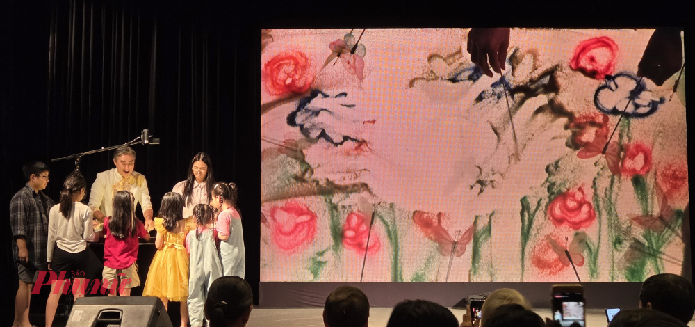 Nghệ sĩ Trí Đức Liên hoan sân khấu Thiếu nhi quốc tế Neapolishướng dẫn các em nhỏ tương tác với bàn chiếu tạo hình ảnh những cánh bướm vờn trên cánh hoa - Ảnh: Ngọc Tuyết