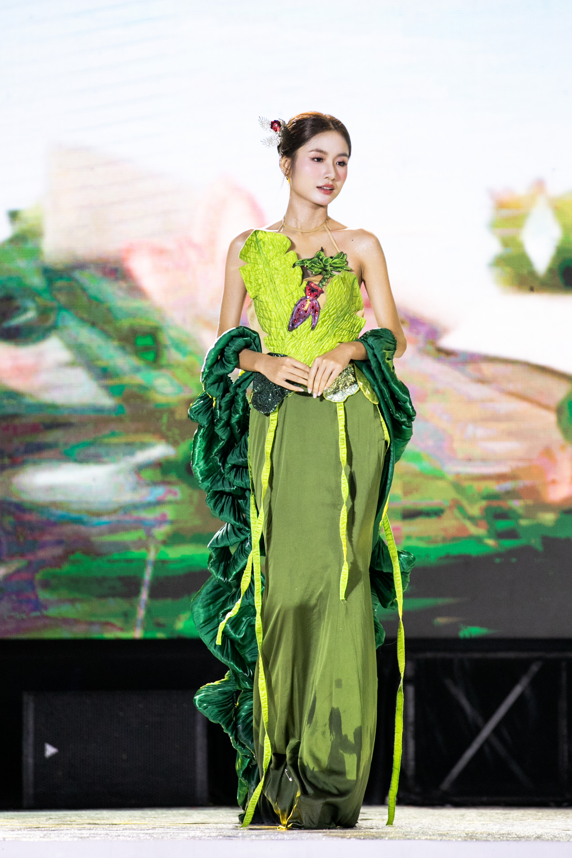 Cũng tại sự kiện, cô thay đổi trang phục khác mang đến hình ảnh sáng tạo và tinh thần gắn kết với thiên nhiên. Bộ váy lấy cảm hứng từ sắc xanh của lá, kết hợp tinh tế giữa hai tông xanh non và xanh rêu, gợi cảm giác tươi mát, tràn đầy sức sống. 