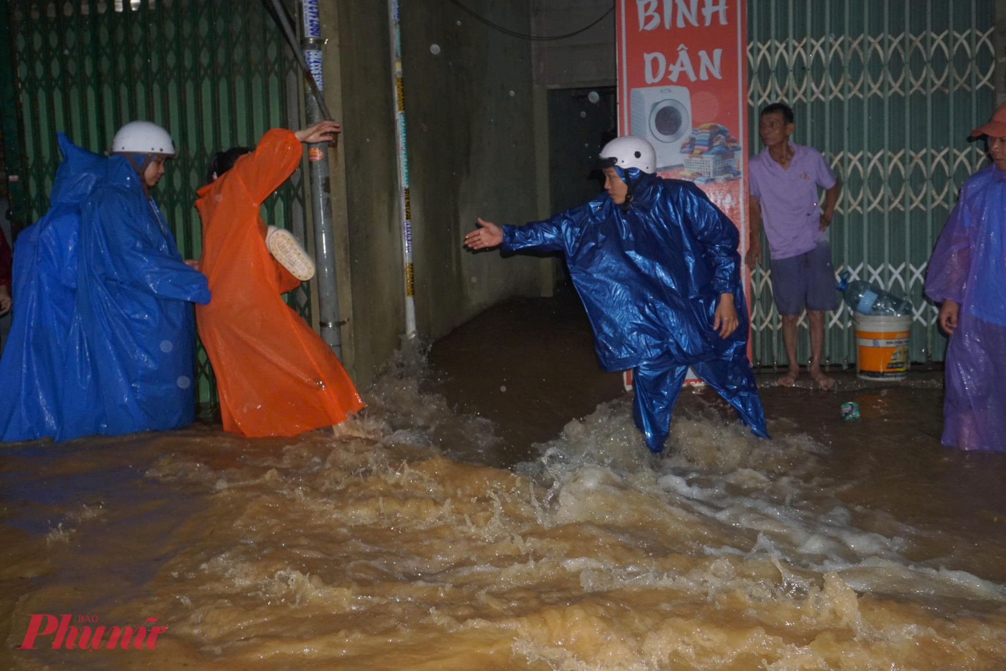 Người dân phải hợp sức dìu nhau qua dòng nước để tránh bị cuốn trôi.