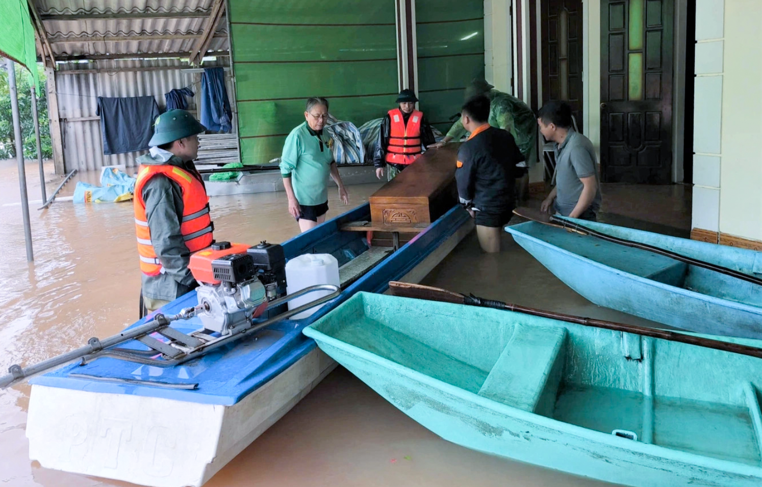 Lực lượng chức năng xã Cẩm Bình dùng ca nô hỗ trợ gia đình cụ Q. chở quan tài ra khỏi khu vực ngập lụt đi hỏa táng - Ảnh: Khánh Trung