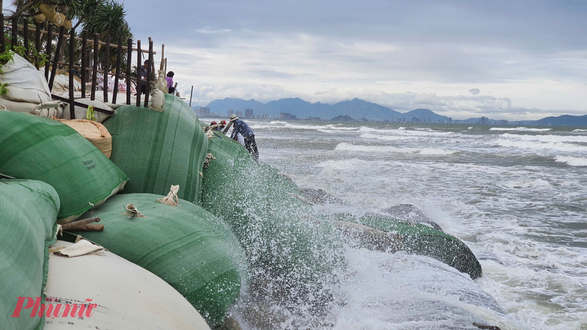 Người dân đang khẩn trương gia cố bờ kè tạm trước dự báo sóng biển cao.