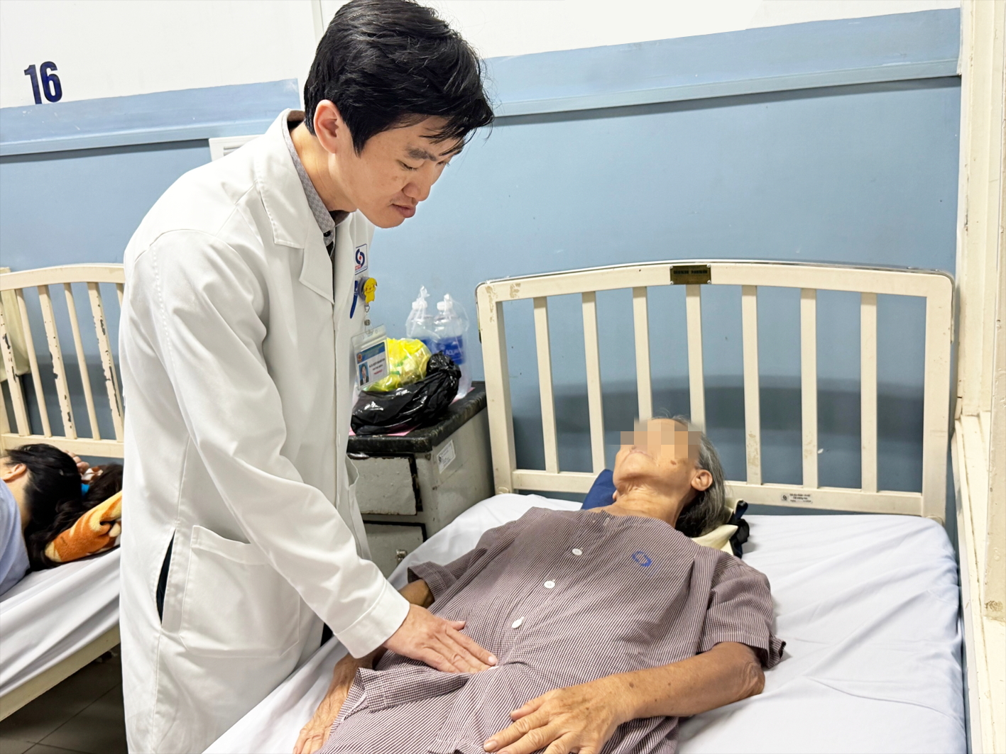 Bác sĩ  Nguyễn Phạm Huy Hùng khám cho một phụ nữ lớn tuổi phải nhập viện do phát hiện bệnh trễ 