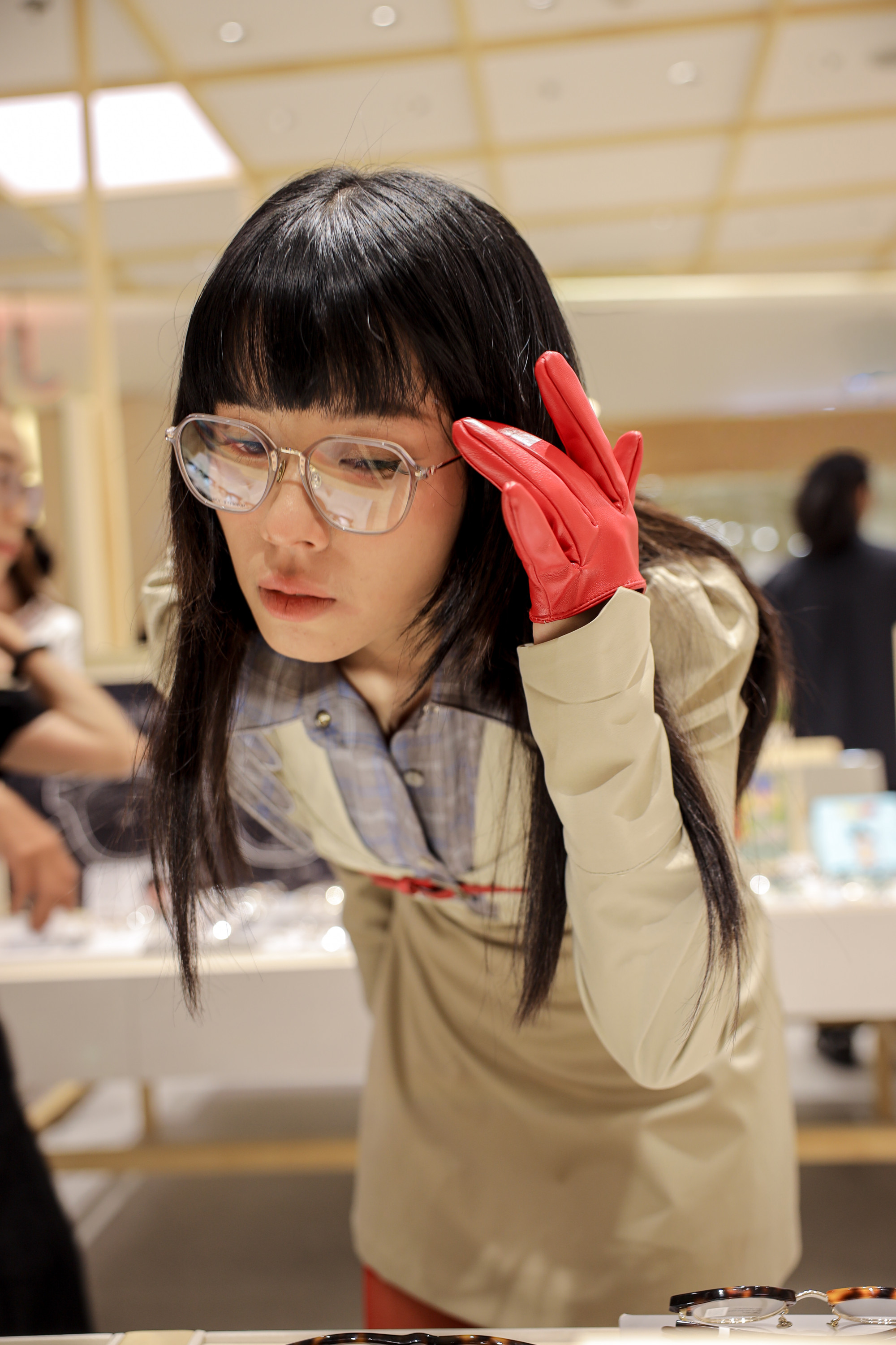 Blogger thời trang Mây Chi kết hợp sơ mi caro cổ điển và váy khoác dáng dài màu be, tạo nên vẻ ngoài vừa thanh lịch vừa phá cách. Hoàn thiện tổng thể là chiếc kính gọng trong suốt bản lớn, vừa mang hơi hướng retro, vừa tạo cảm giác sang trọng, hiện đại. Món phụ kiện này không chỉ làm sáng gương mặt mà còn giúp cân bằng tổng thể trang phục, khiến người đeo toát lên vẻ thông minh, tinh tế nhưng không kém phần khác biệt.