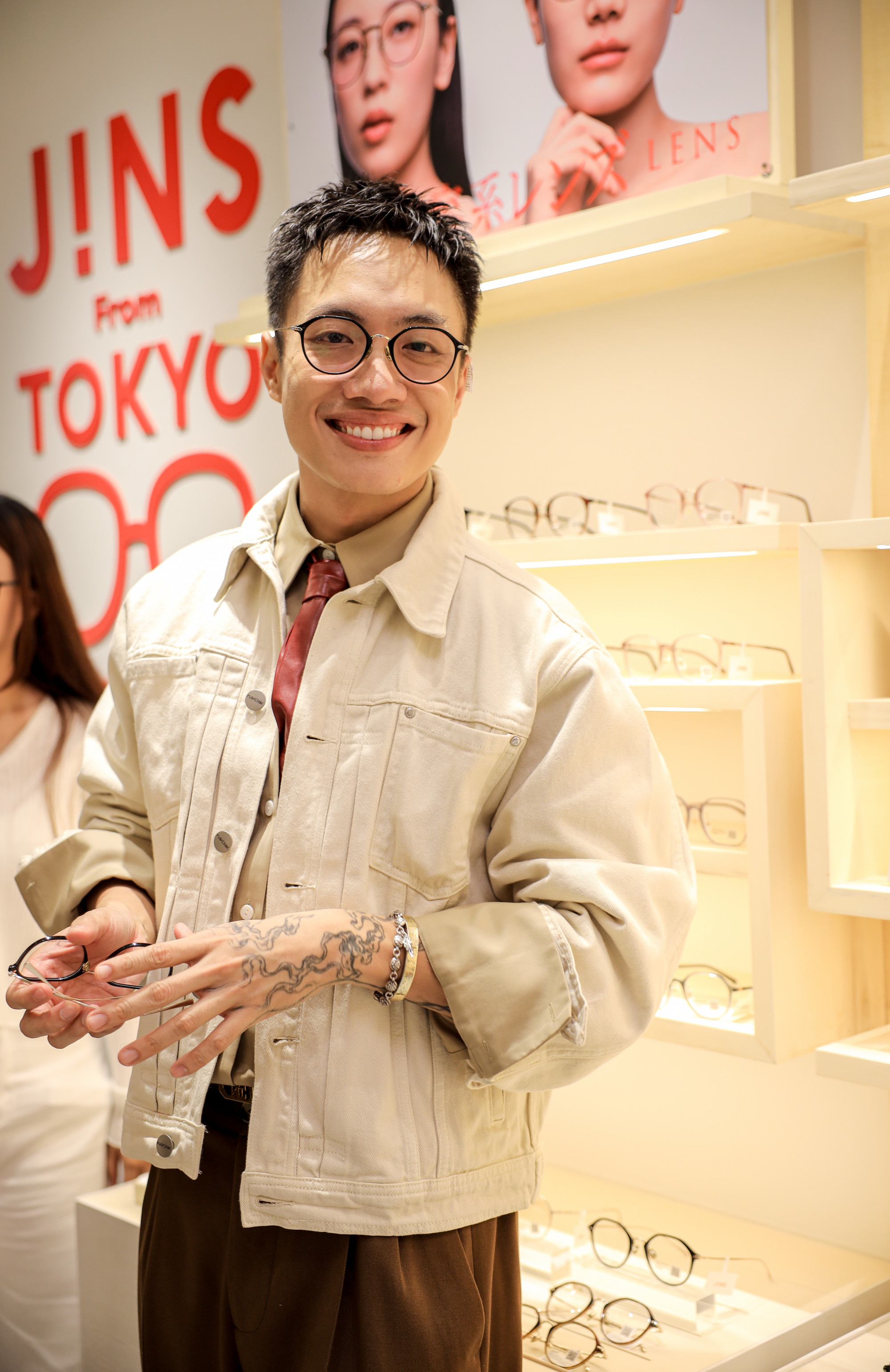 Giám đốc sáng tạo Alex Fox gây ấn tượng với phong cách thời trang tinh tế và hiện đại, mang hơi hướng smart-casual đặc trưng. Anh chọn áo sơ mi màu be kết hợp cùng áo khoác denim sáng màu tạo nên tổng thể hài hòa, vừa năng động vừa lịch thiệp. Điểm nhấn nổi bật nhất là chiếc kính gọng tròn màu đen, phụ kiện hoàn hảo làm nổi bật gương mặt và tôn lên nét thông minh, phóng khoáng.