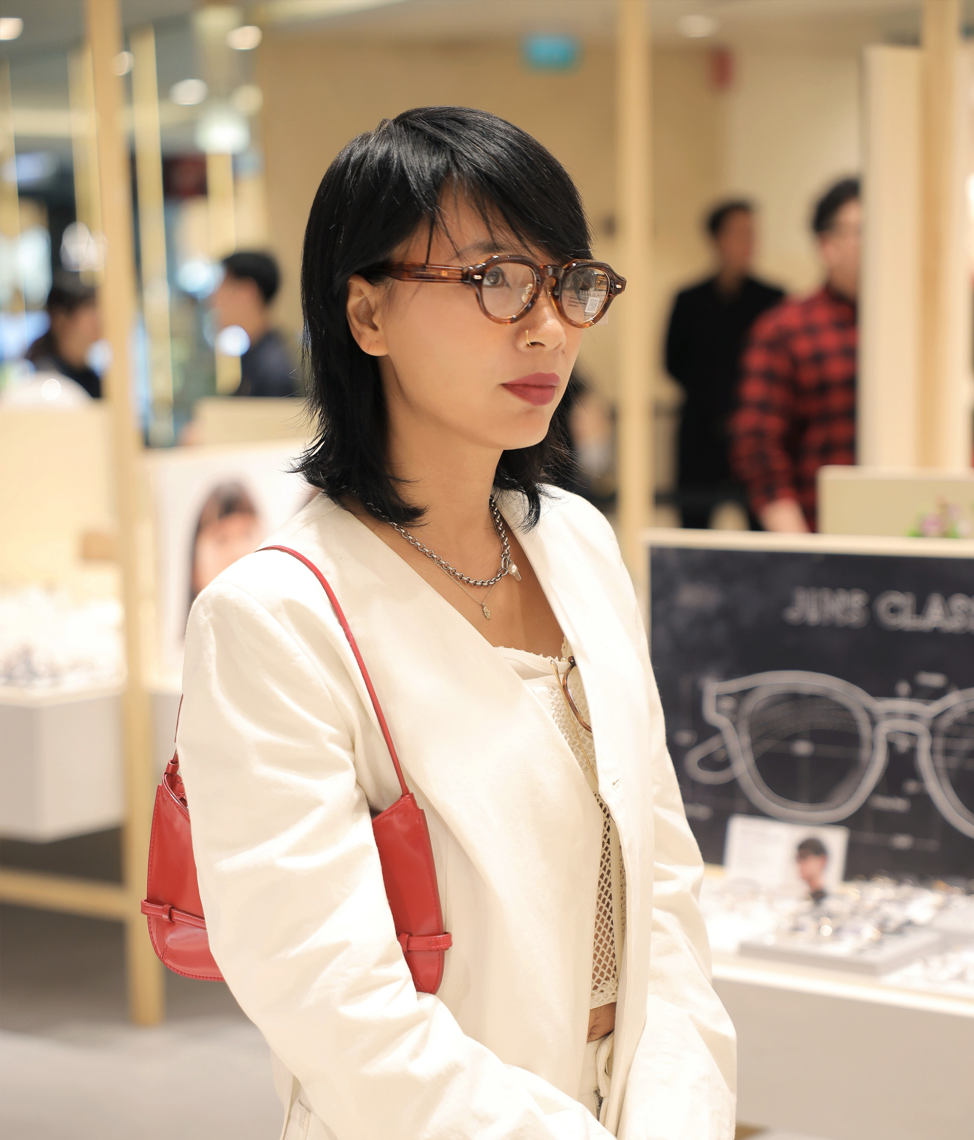 Trong set đồ mang tinh thần tối giản nhưng tinh tế, MC Thuỳ Minh phối chiếc kính gọng nâu trở thành điểm nhấn nổi bật, giúp tổng thể trang phục thêm chiều sâu và cá tính. Sự kết hợp giữa áo khoác trắng sáng, áo lưới nhẹ bên trong và túi xách đỏ nhỏ nhắn tạo nên một diện mạo hiện đại, vừa phóng khoáng vừa sắc sảo. Mẫu kính không chỉ đóng vai trò phụ kiện thời trang mà còn góp phần định hình phong cách.