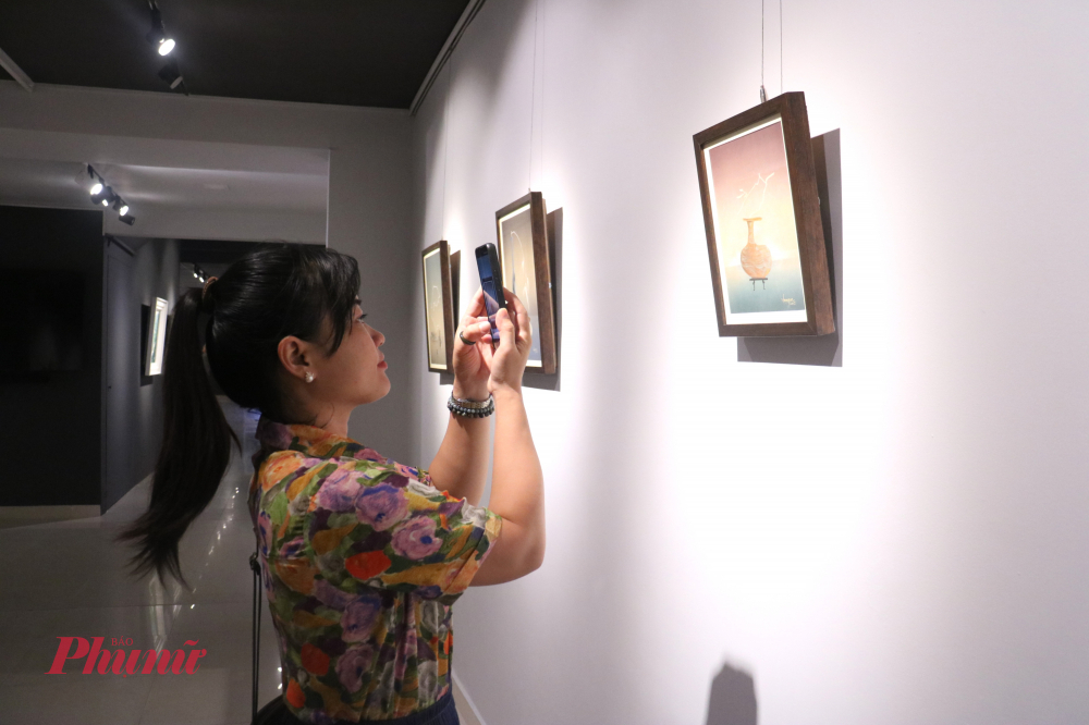 Khách tham dự ghi lại khoảnh khắc bên các tác phẩm lụa của họa sĩ Lâm Gia Huấn - Ảnh: Phương Nhã