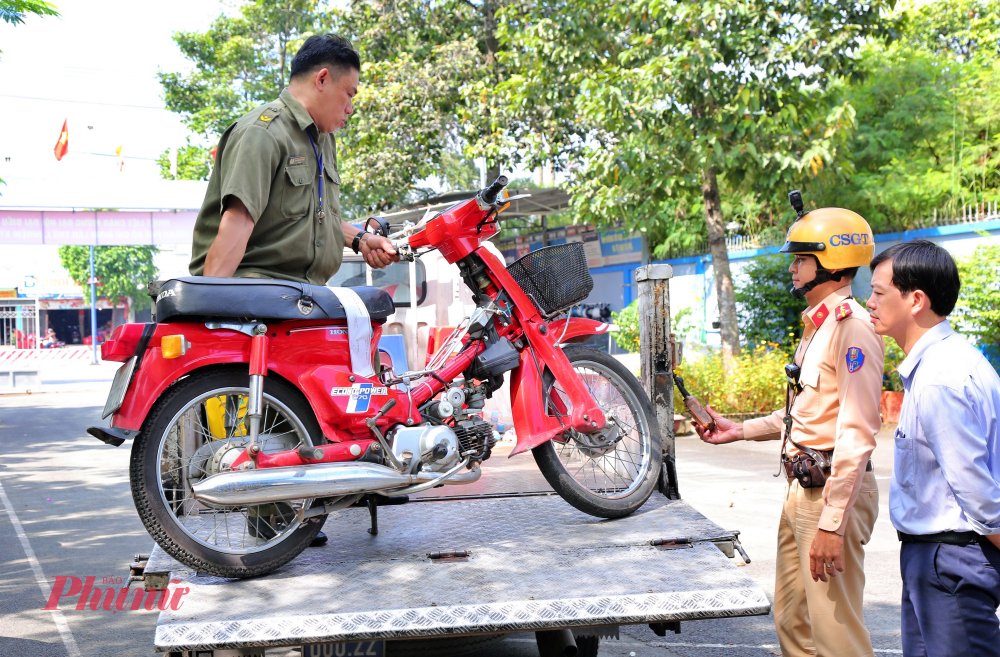 Xe máy do học sinh điều khiển đến trường bị tạm giữ đưa lên xe chuyên dụng - Ảnh: TQ