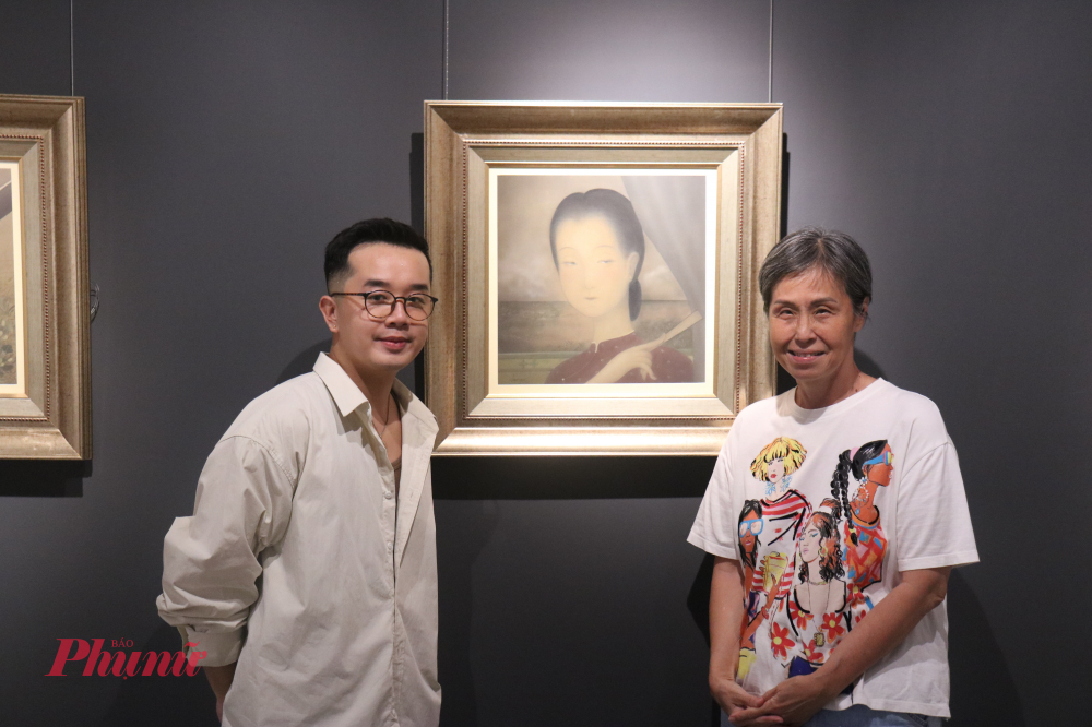 Họa sĩ Lâm Gia Huấn (trái) lưu dấu khoảnh khắc cùng bạn bè bên cạnh tác phẩm Vén rèm - Ảnh: Phương Nhã