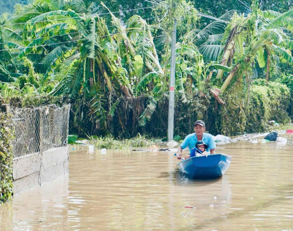 Người dân di chuyển bằng ghe qua những đoạn ngập lụt