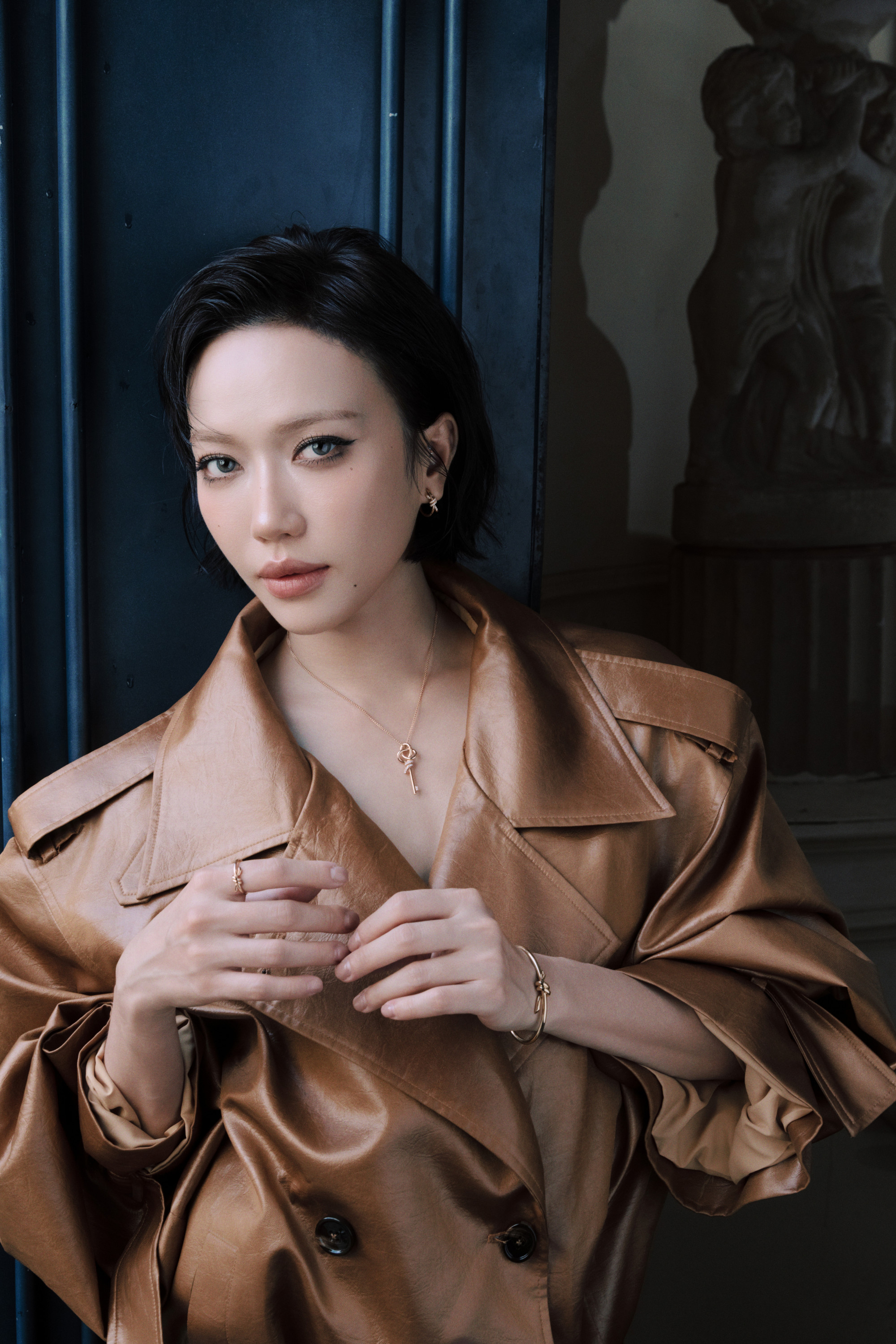 Ở outfit khác, nữ diễn viên chuyển sang hình ảnh hiện đại, cá tính hơn với chiếc trench coat da màu caramel. Chất liệu da mềm, phom dáng rộng và cách tạo nếp tự nhiên mang đến cảm giác phóng khoáng nhưng vẫn giữ được nét quý phái