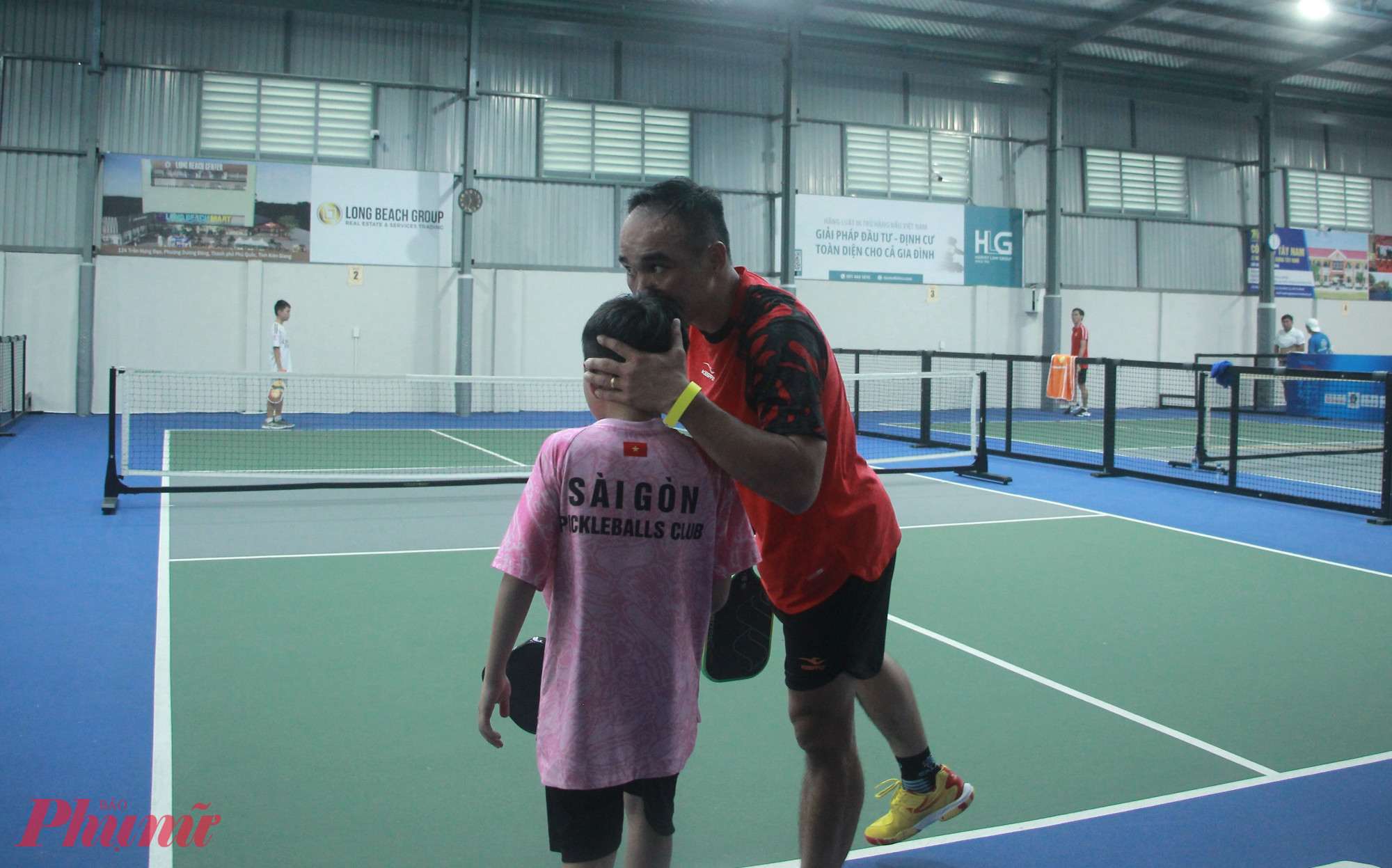 Anh Đặng Phú Kiện ôm hôn động viên khi thấy con chịu áp lực và đánh hỏng bóng liên tục. Hai cha con anh sau đó đã lội ngược dòng để dành chiến thắng - Ảnh: Nguyễn Loan