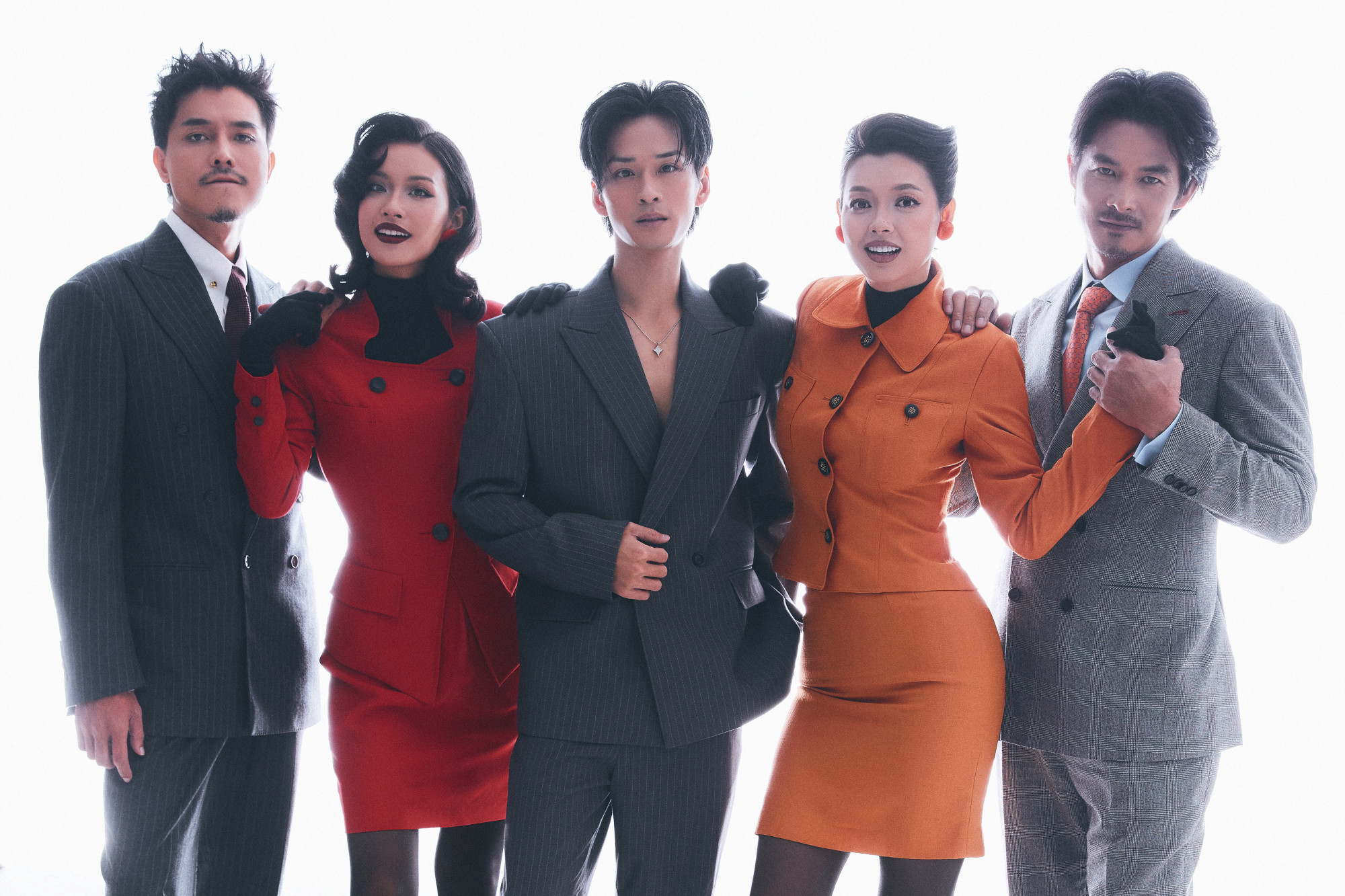 Quách Ngọc Ngoan diện vest xám tro, thắt cà vạt đỏ rượu vang, gương mặt sắc lạnh, toát lên vẻ từng trải và nội lực. Xuân Văn nổi bật trong outfit cam rực rỡ, kết hợp găng tay đen và giày cao gót ánh kim, mang đậm tinh thần nữ quyền hiện đại.