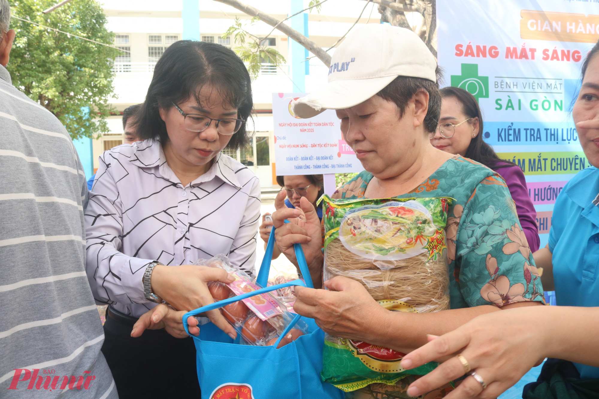 Bà Huỳnh Kim Loan – Phó chủ tịch thường trực Ủy ban MTTQ Việt Nam phường An Phú Đông, Chủ tịch Hội LHPN phường (bìa trái) – trao quà từ gian hàng “0 đồng” cho các dì, các chị - Ảnh: Mẫn Nhi