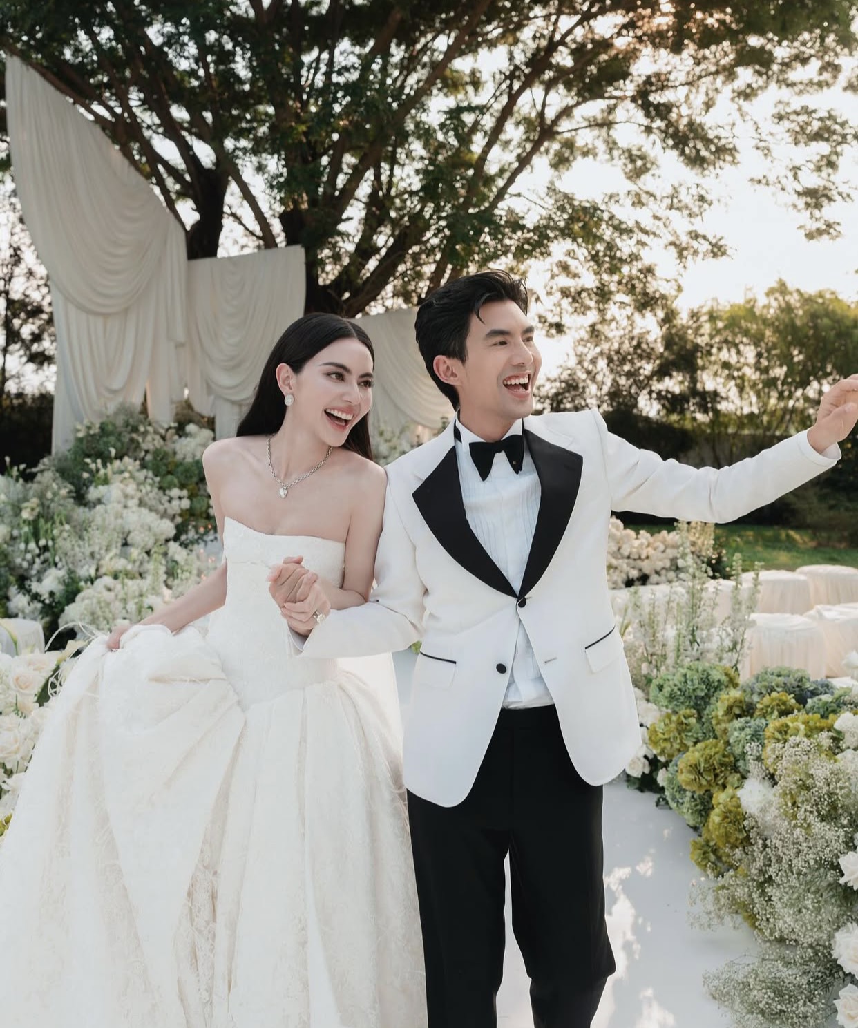 Sánh đôi bên cô dâu, chú rể Ter Chantavit diện bộ tuxedo trắng đen được Gucci thiết kế riêng, phối áo sơ mi trắng cổ điển và nơ đen bản lớn. Sự kết hợp ton-sur-ton của cặp đôi tạo nên tổng thể hài hòa, tinh tế và đậm dấu ấn thời trang Ý.