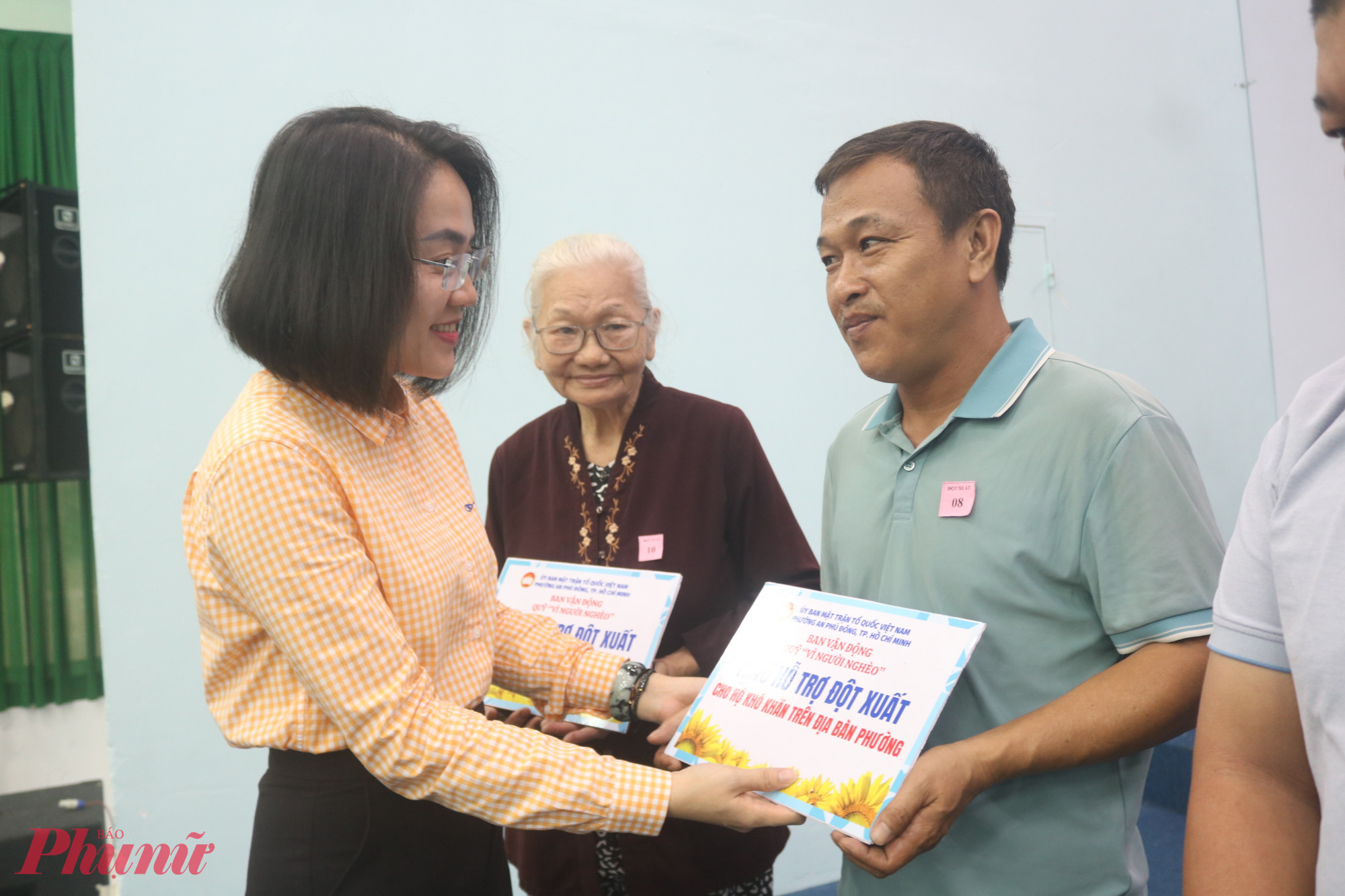 Bà Hồ Thị Thủy – Phó bí thư thường trực Đảng ủy phường An Phú Đông – trao bảng tượng trưng nội dung hỗ trợ đột xuất và động viên đại diện các hộ dân - Ảnh: Mẫn Nhi