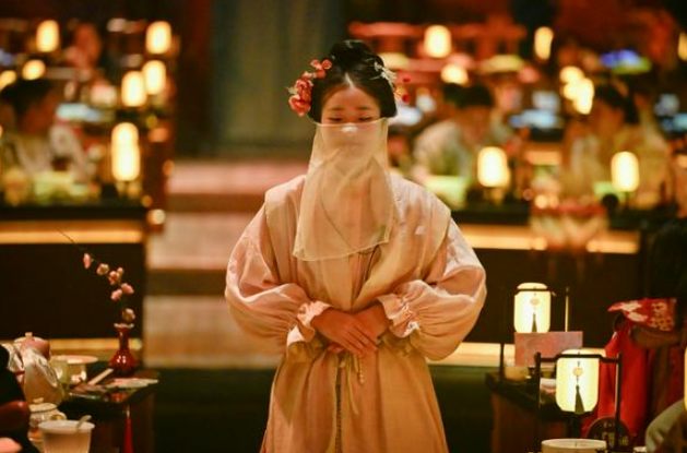 Một nhân viên phục vụ trong trang phục truyền thống của Trung Quốc đang chờ phục vụ khách hàng tại một nhà hàng sân khấu ở Bắc Kinh