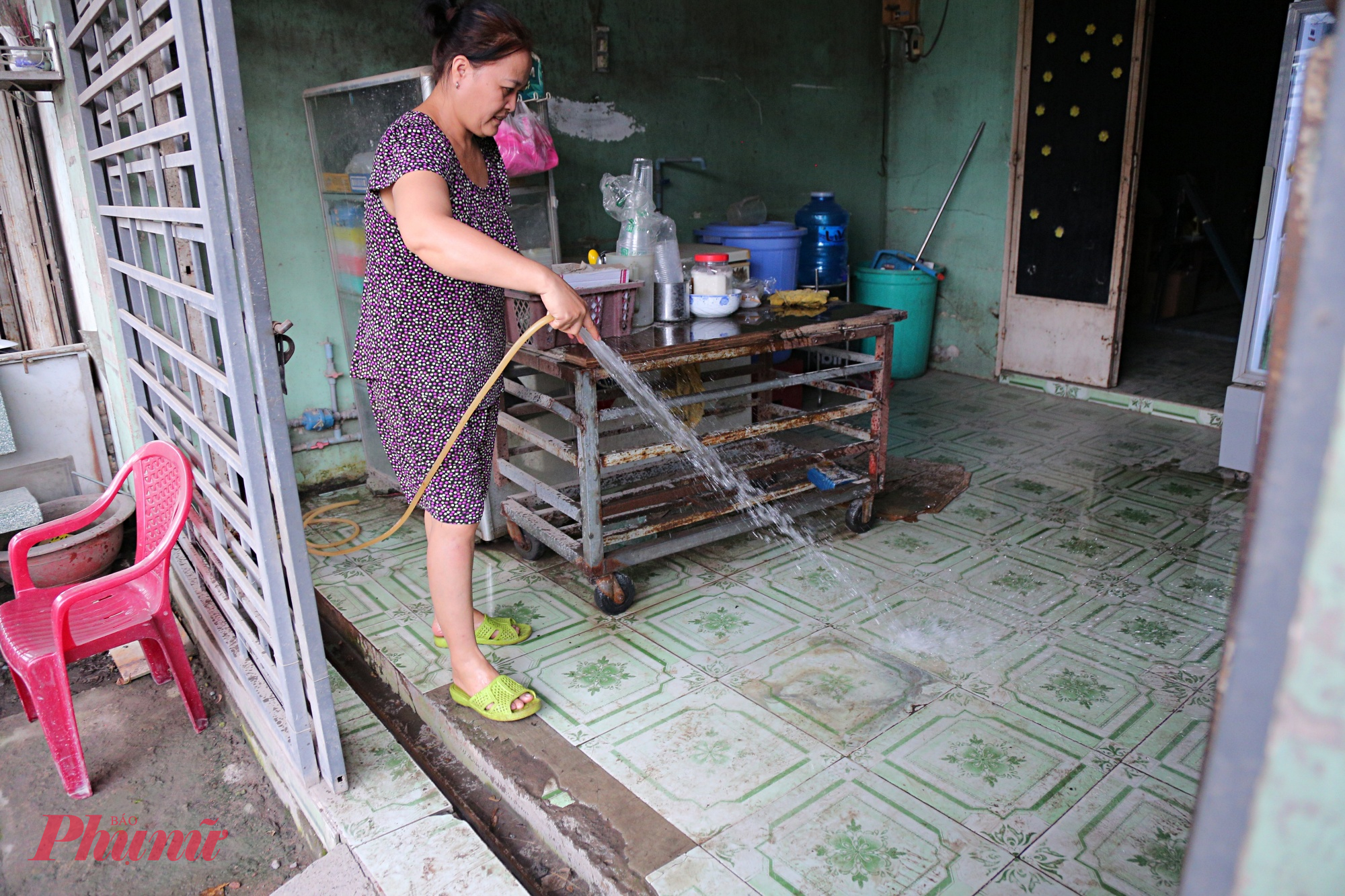 Đường cửa ngõ TPHCM xuống cấp, bụi dày phủ trắng nhà dân như sương mù Chị Hoa đang xịt nước rửa nền nhà để giảm bụi