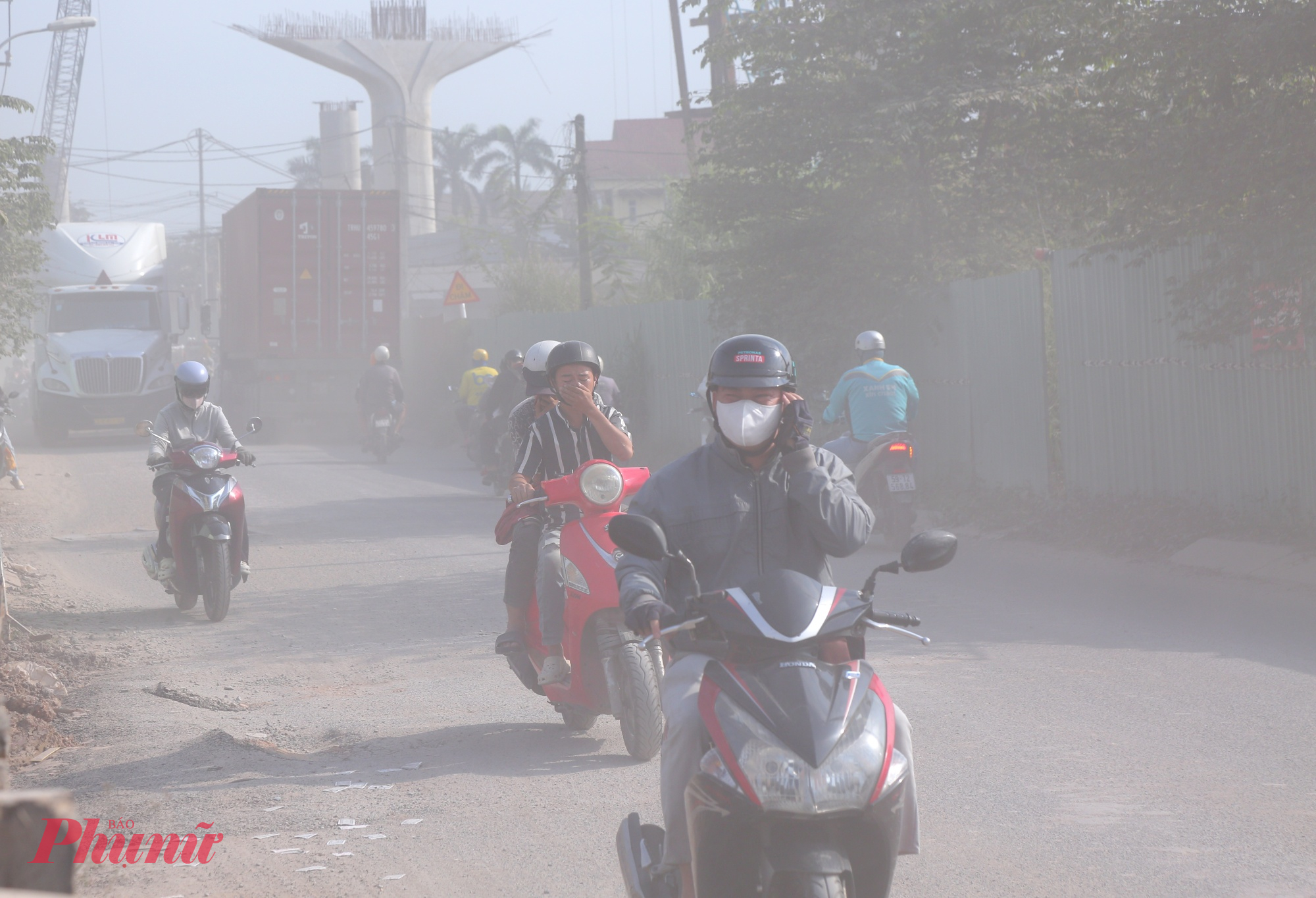 Đường cửa ngõ TPHCM xuống cấp, bụi dày phủ trắng nhà dân như sương mù Hầu như người dân đi qua đường Nguyễn Xiển đều trùm kín mít và dùng tay bịt mũi vì bụi dày đặc.