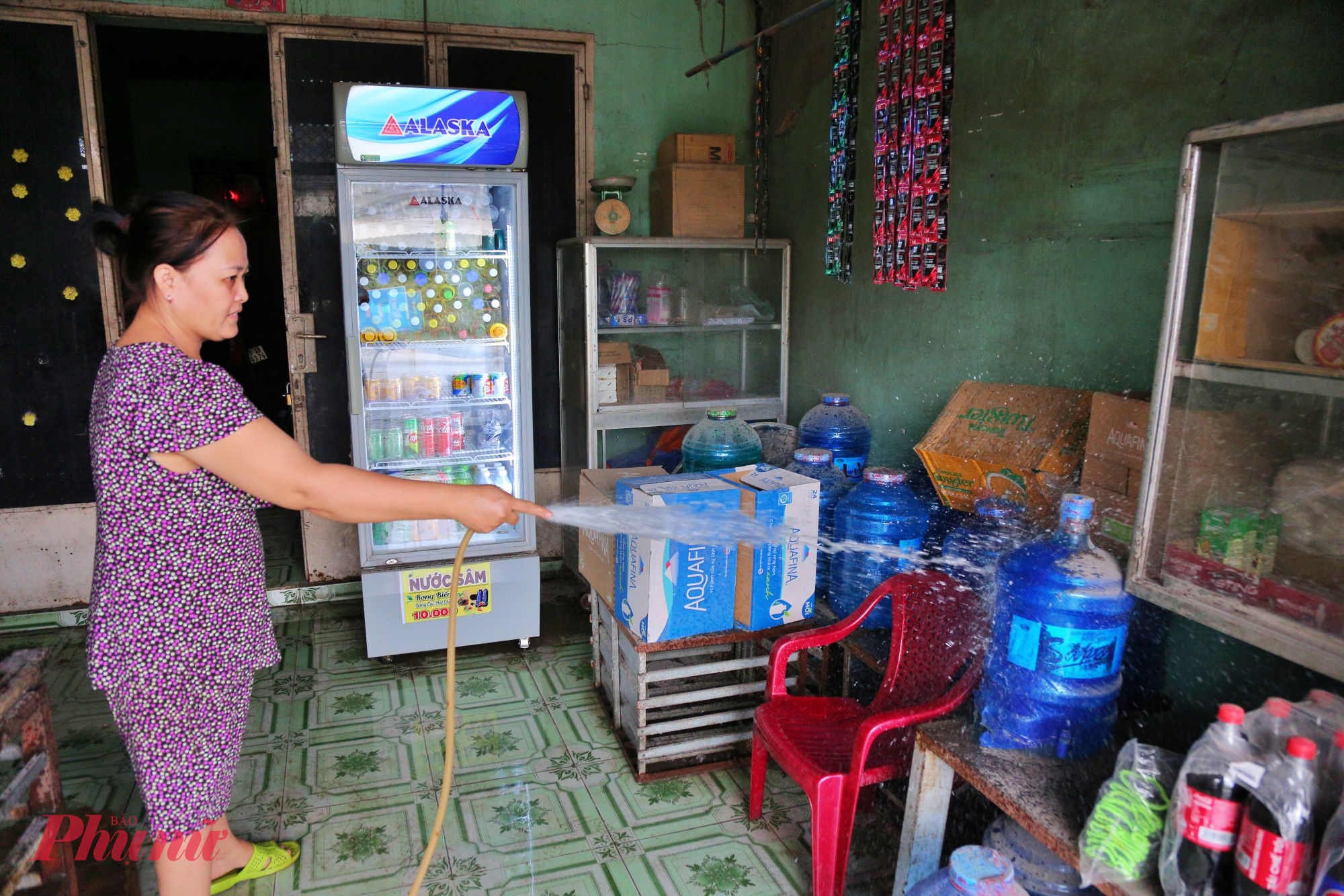 Đường cửa ngõ TPHCM xuống cấp, bụi dày phủ trắng nhà dân như sương mù Chị Hoa xịt nước rửa hàng hóa để khách còn ghé mua.