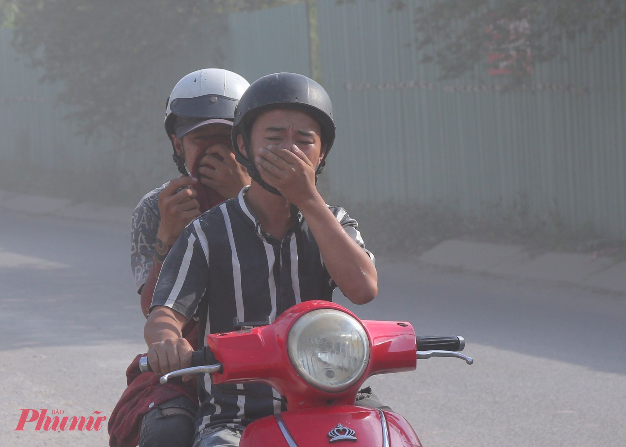 Đường cửa ngõ TPHCM xuống cấp, bụi dày phủ trắng nhà dân như sương mù Hai người đàn ông đi xe máy không đeo khẩu trang và nhăn mặt vì quá bụi