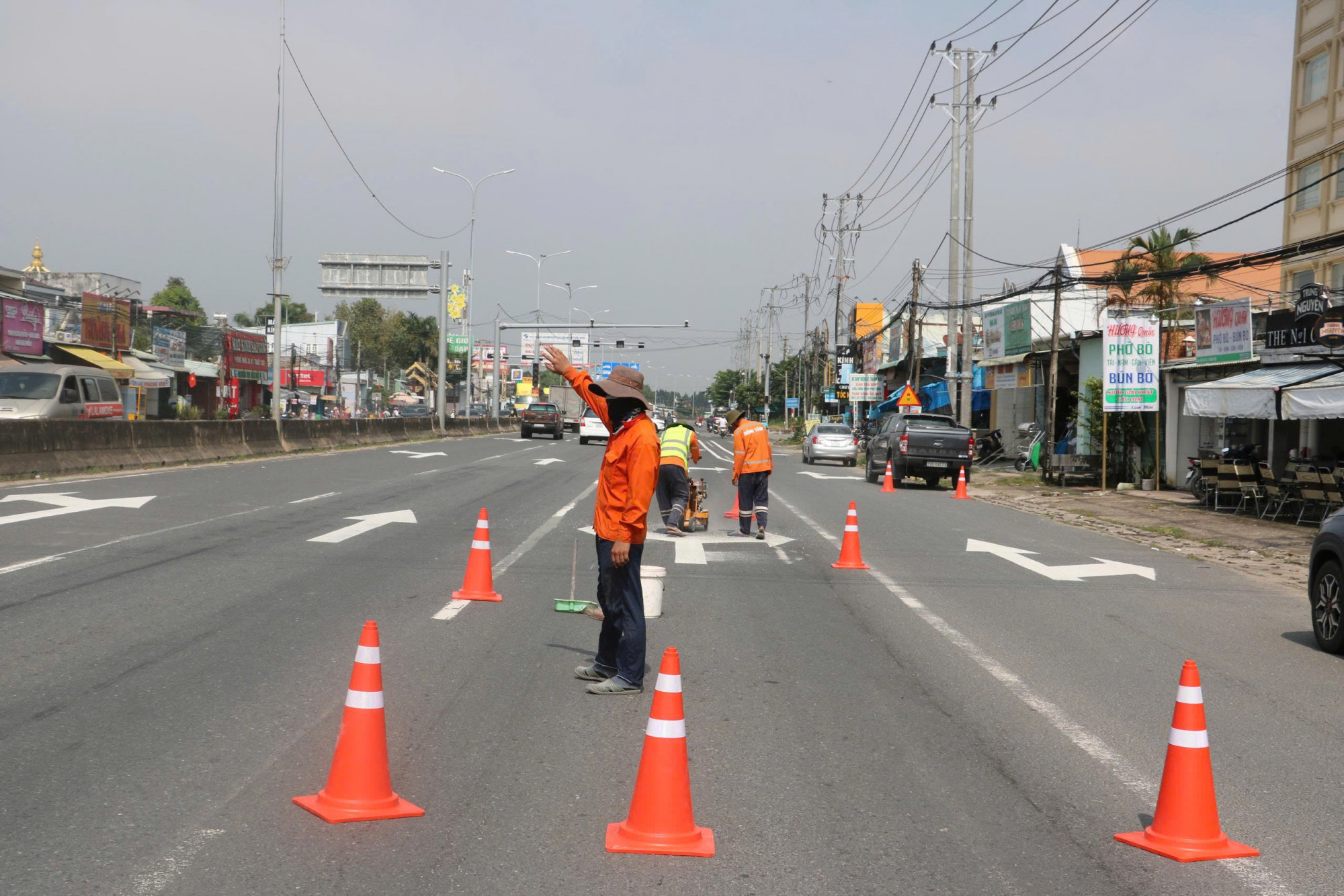 Công nhân thực hiện kẻ vạch phân làn trên QL51 đoạn qua địa bàn phường Tân Phước. Ảnh: Quang Hưng