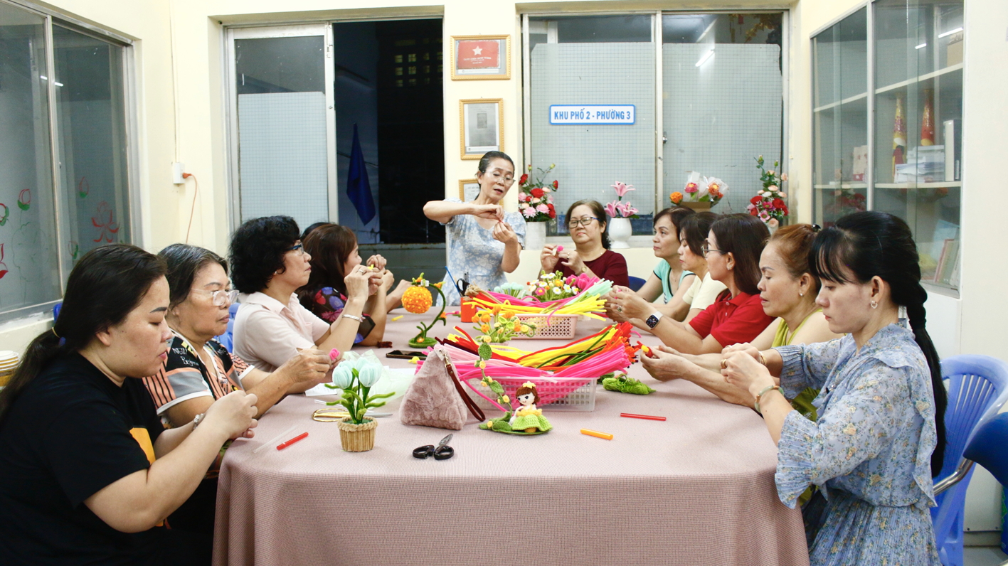 Bà Vũ Thị Lam (đứng) - Chi hội trưởng Chi hội Phụ nữ khu phố 2 - đang hướng dẫn chị em  làm hoa từ kẽm nhung