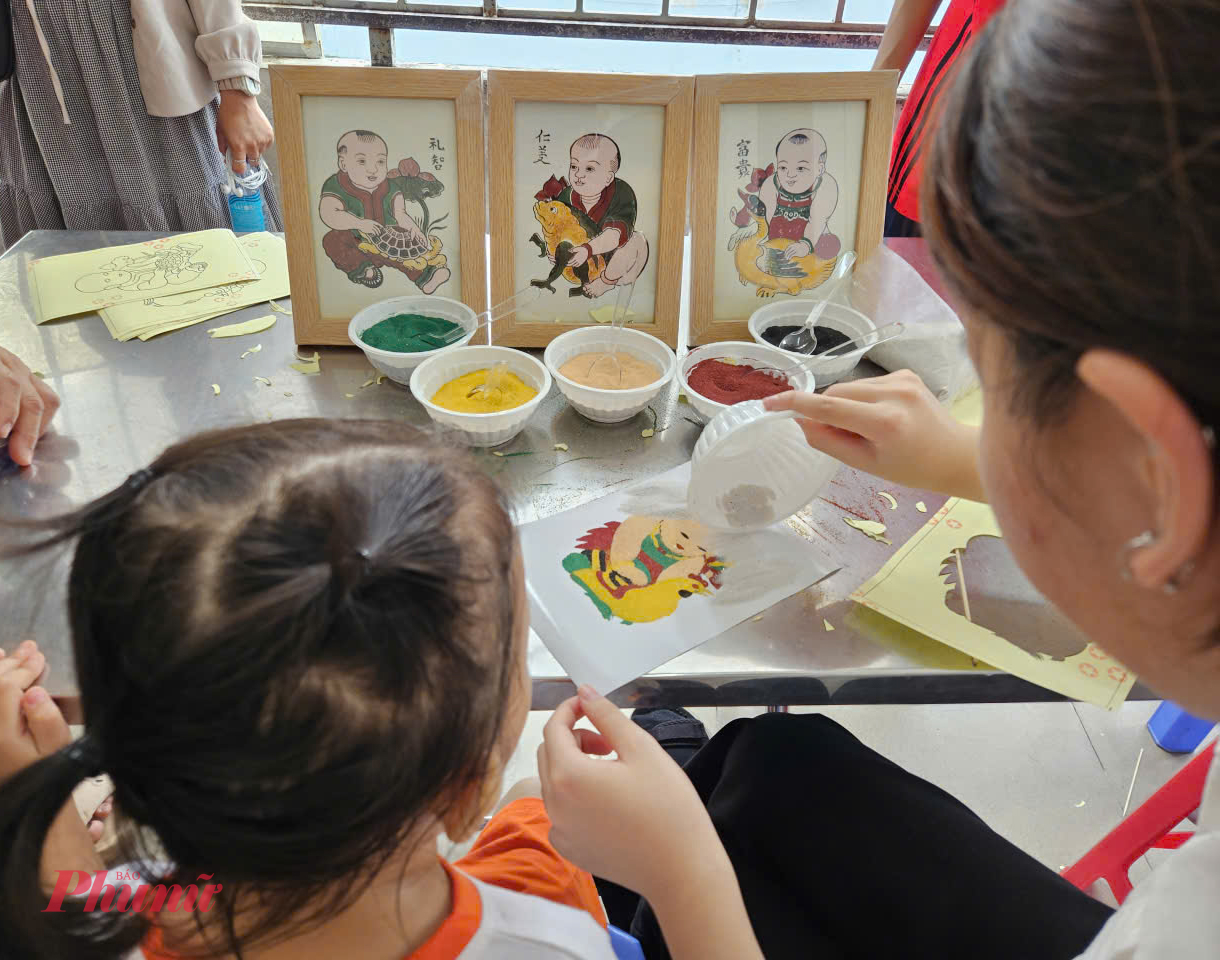 Với sự hướng dẫn của các tình nguyện viên là sinh viên trường Đại học , các bé có thể chọn lựa bức tranh cát phong cách tranh đông hồ như 