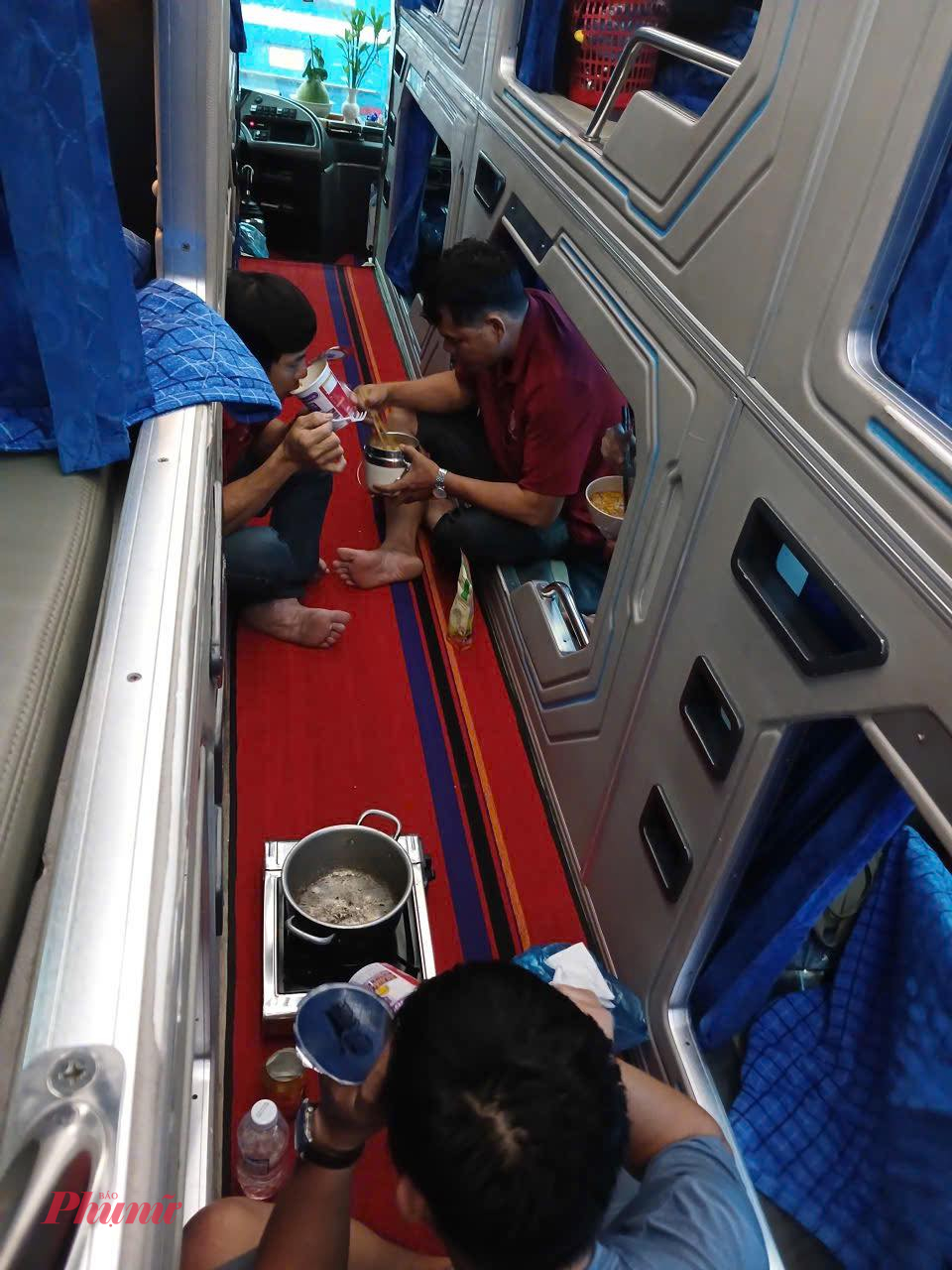 Hành khách nấu mì tôm ăn tạm trong xe tuyến TPHCM - Bình Định trong lúc kẹt xe do Quốc lộ 1 bị ngập nặng đoạn qua Phú Yên - Ảnh: Cuộc Huê 