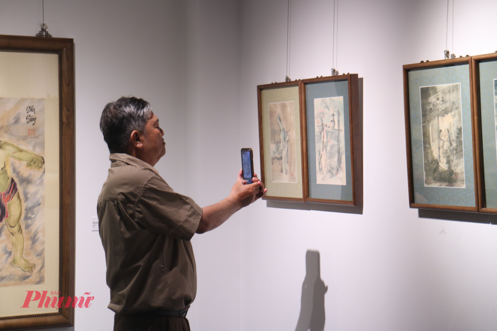 Khách tham dự ghi lại khoảnh khắc bên các tác phẩm của họa sĩ Tú Duyên - Ảnh: Phương Nhã