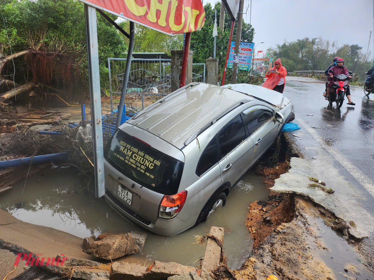 Một chiếc ô tô của người dân bị nước lũ hư hỏng, rơi xuống hố sạt lở. 
