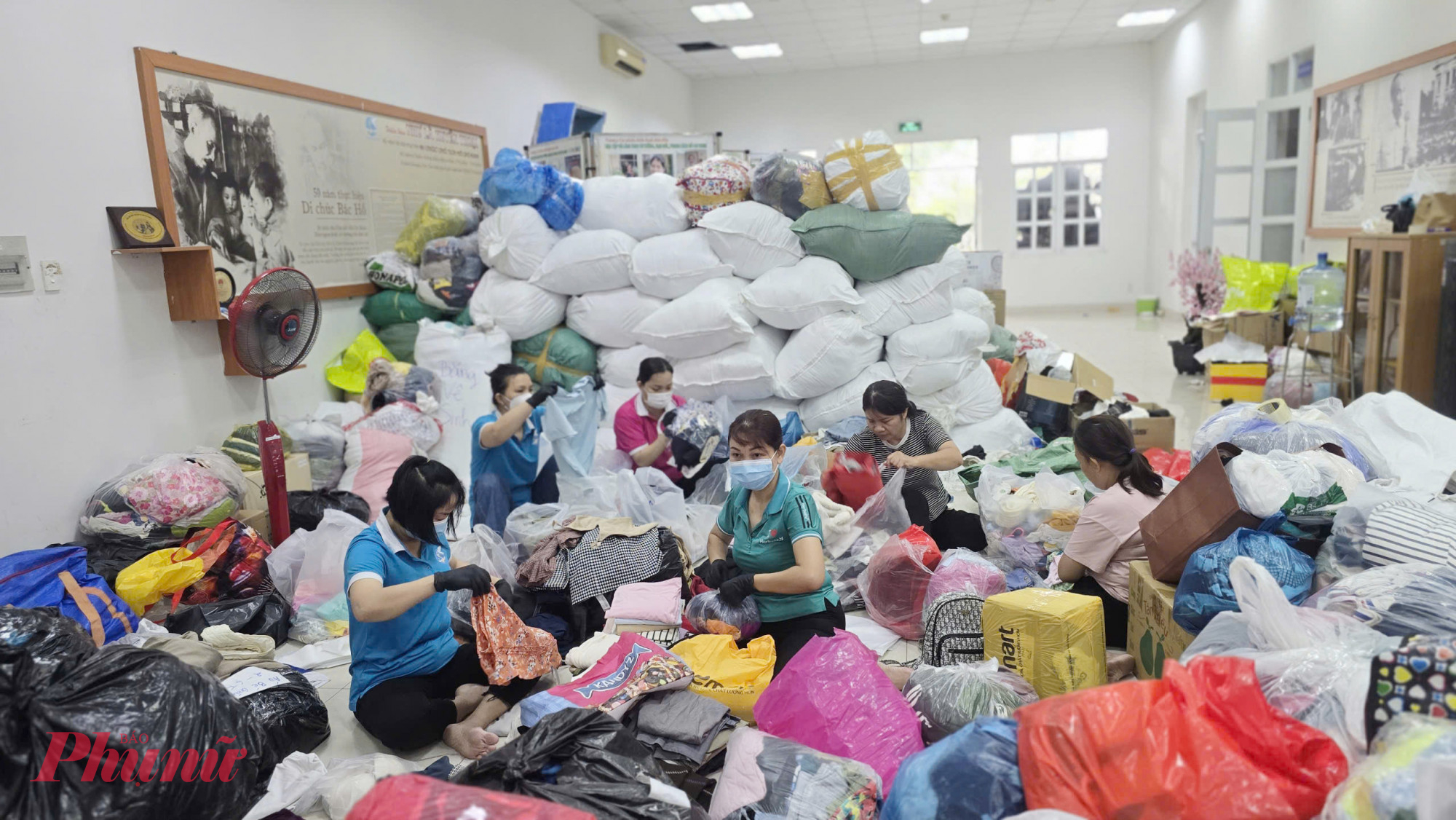 Cán bộ hội viên phụ nữ tham gia phân loại, sắp xếp núi quần áo, hàng hóa, và các nhu yếu phẩm thiết yếu, gửi đến đồng bào bị ảnh hưởng bão lũ 