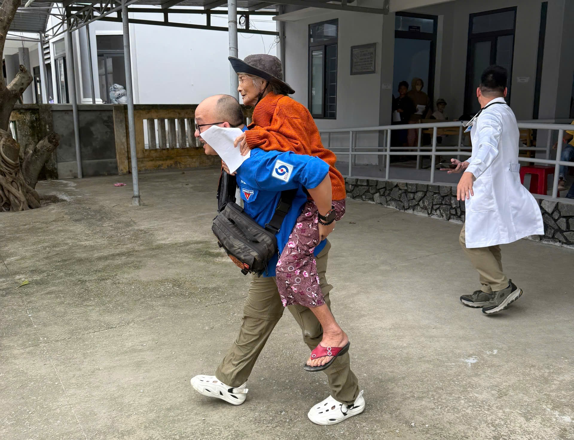 Sau khi được khám bệnh, nhân viên y tế đã cõng bà Xửng ra xe về nhà, ảnh M.T