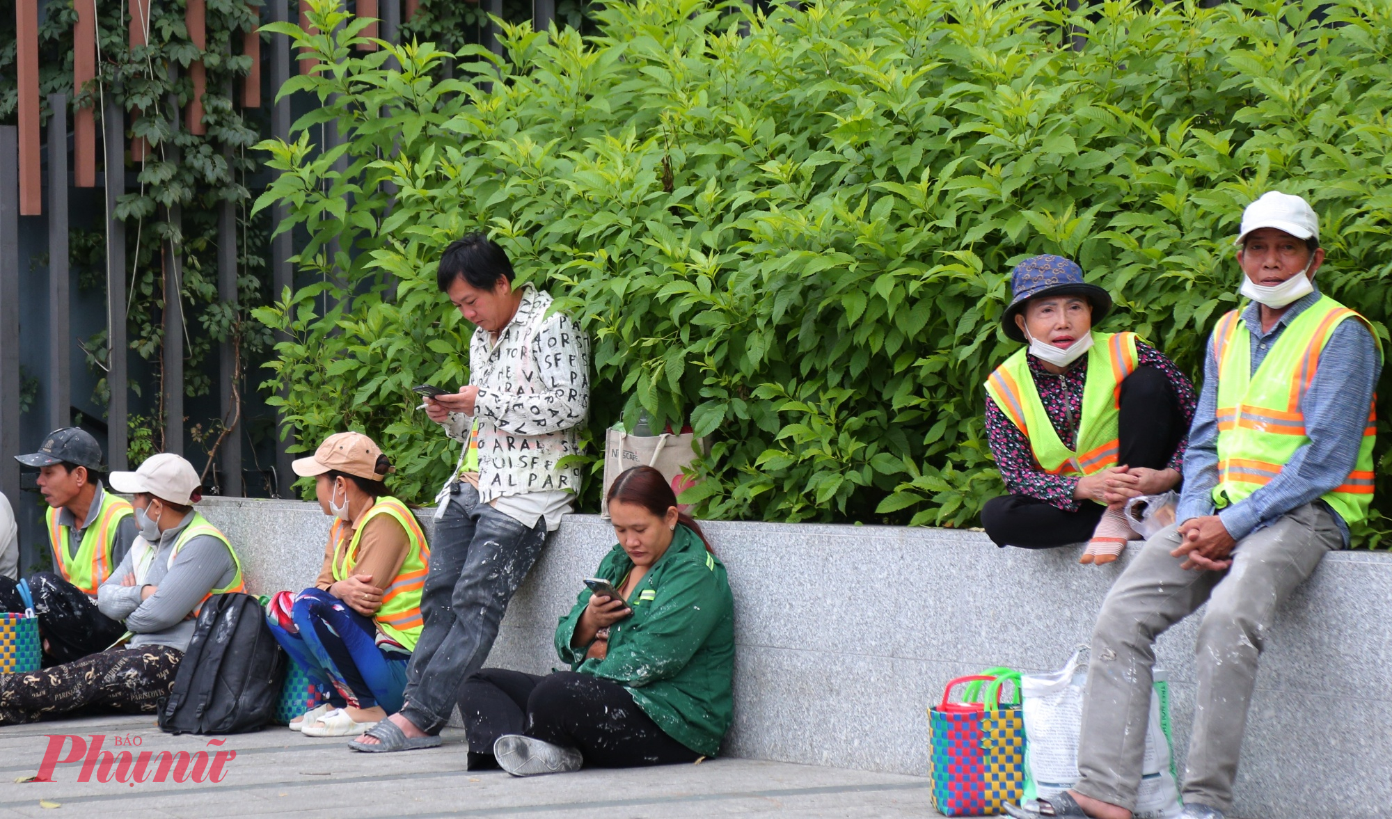 Những anh chị công nhân xây dựng ngồi thu mình tại một góc vì lạnh trong lúc chờ vào công trình làm việc.