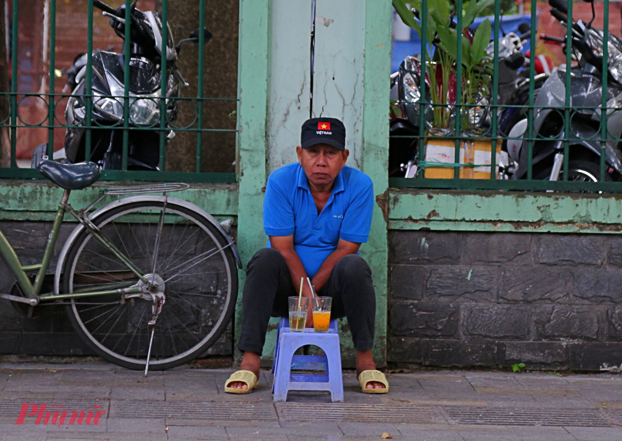 Người đàn ông ngồi co ro uống cà phê gần Thảo Cầm Viên 